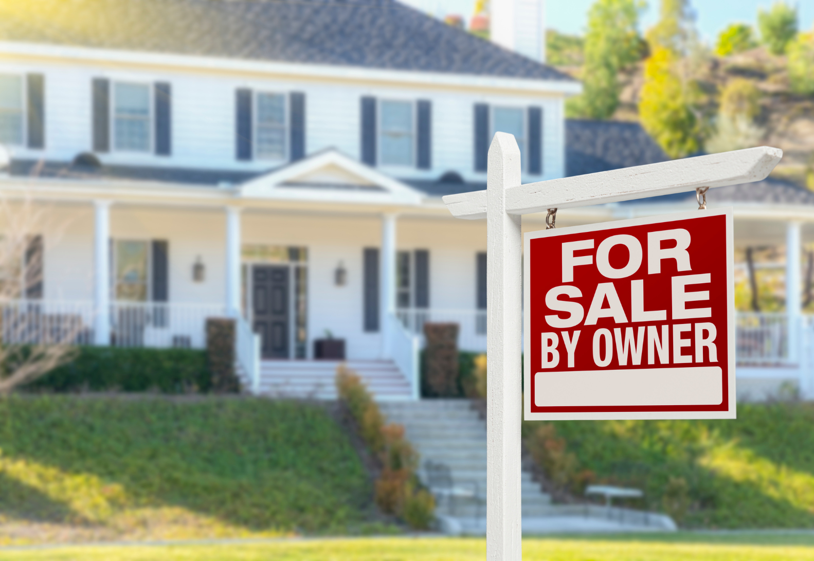 Sign Post showing For Sale By Owner with a house in the background