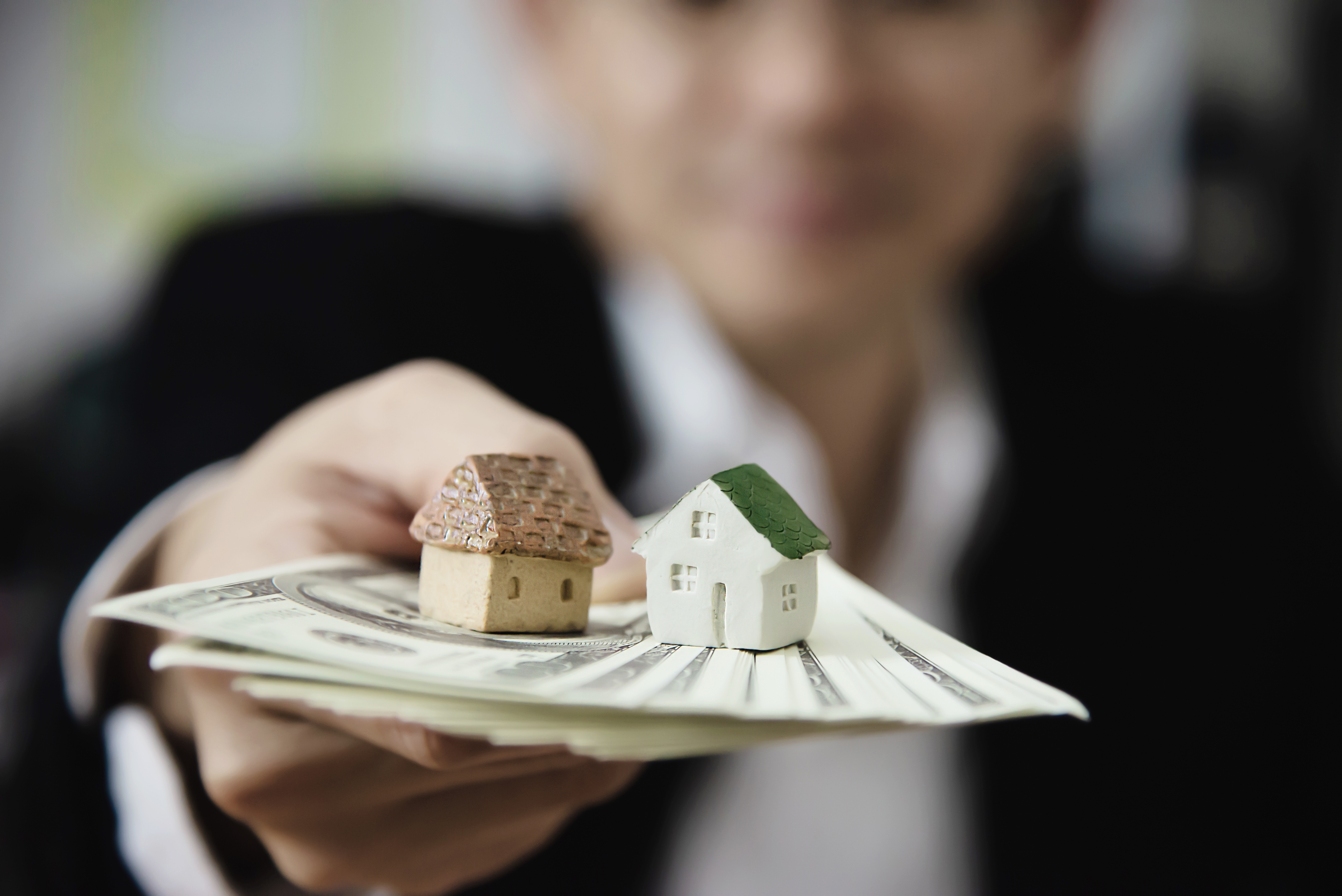 man holding money with little house on top