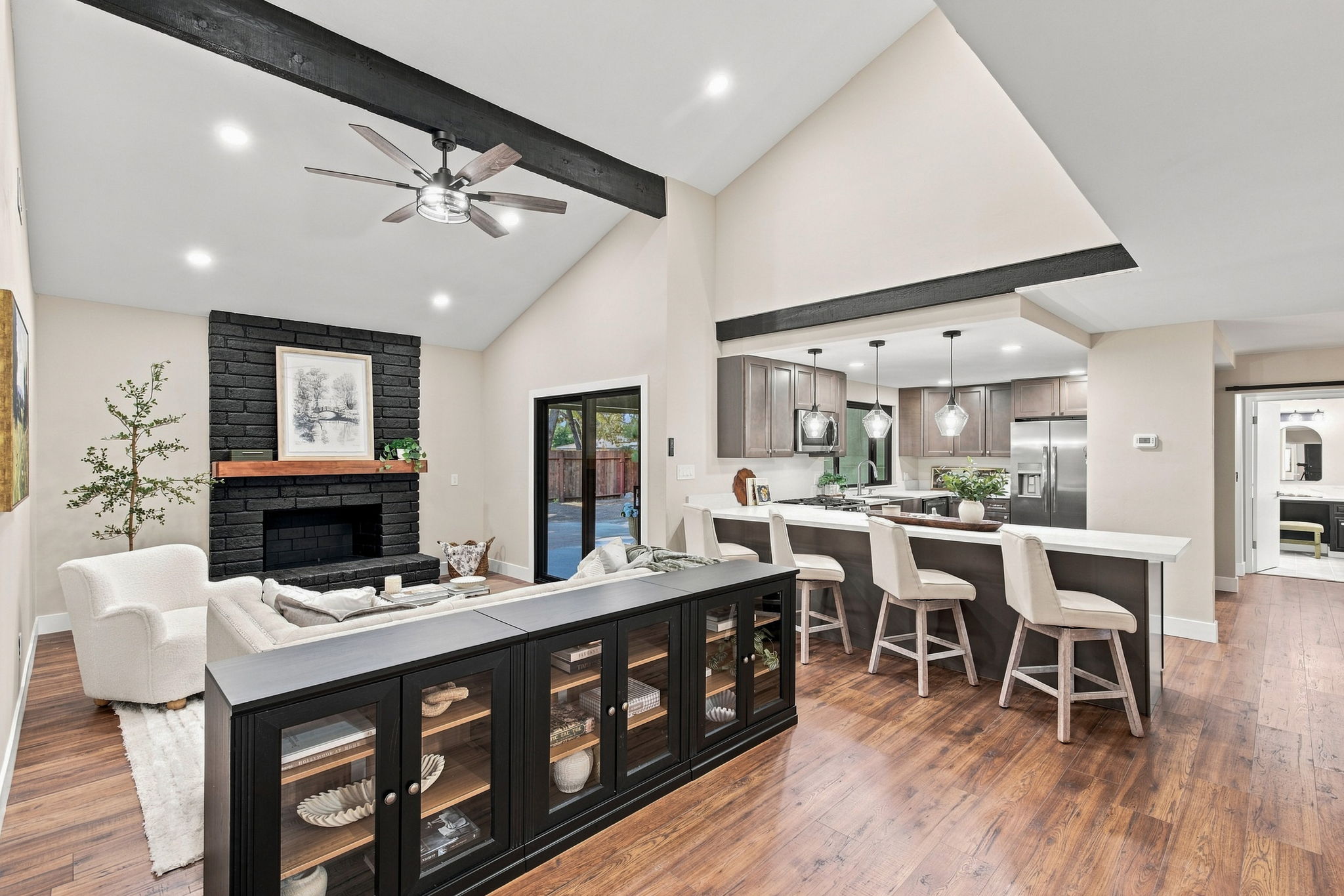 Updated Bakersfield home interior with vaulted ceilings, black brick fireplace, open kitchen, island seating and wood floors.