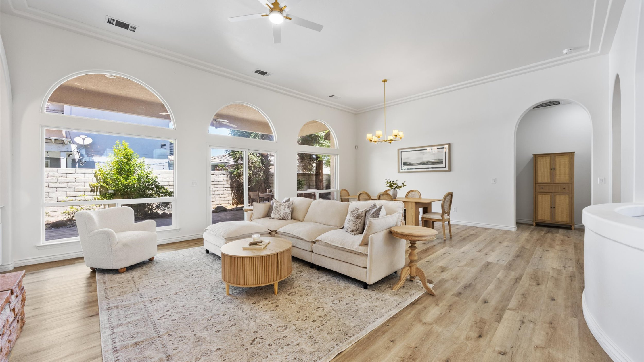 Staged open-concept living and dining room with natural light, neutral decor, and wood flooring in a Bakersfield home