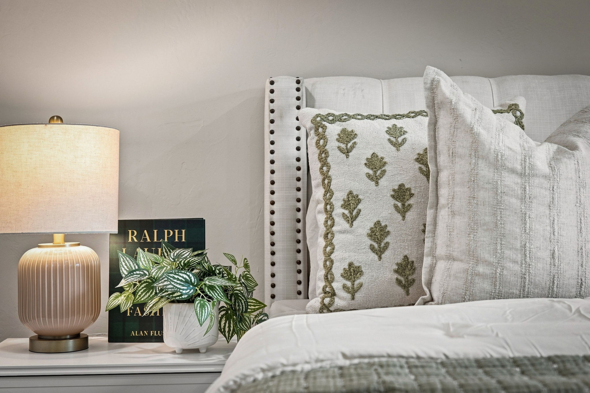 Staged primary bedroom in a Bakersfield home for sale with neutral bedding and green accents