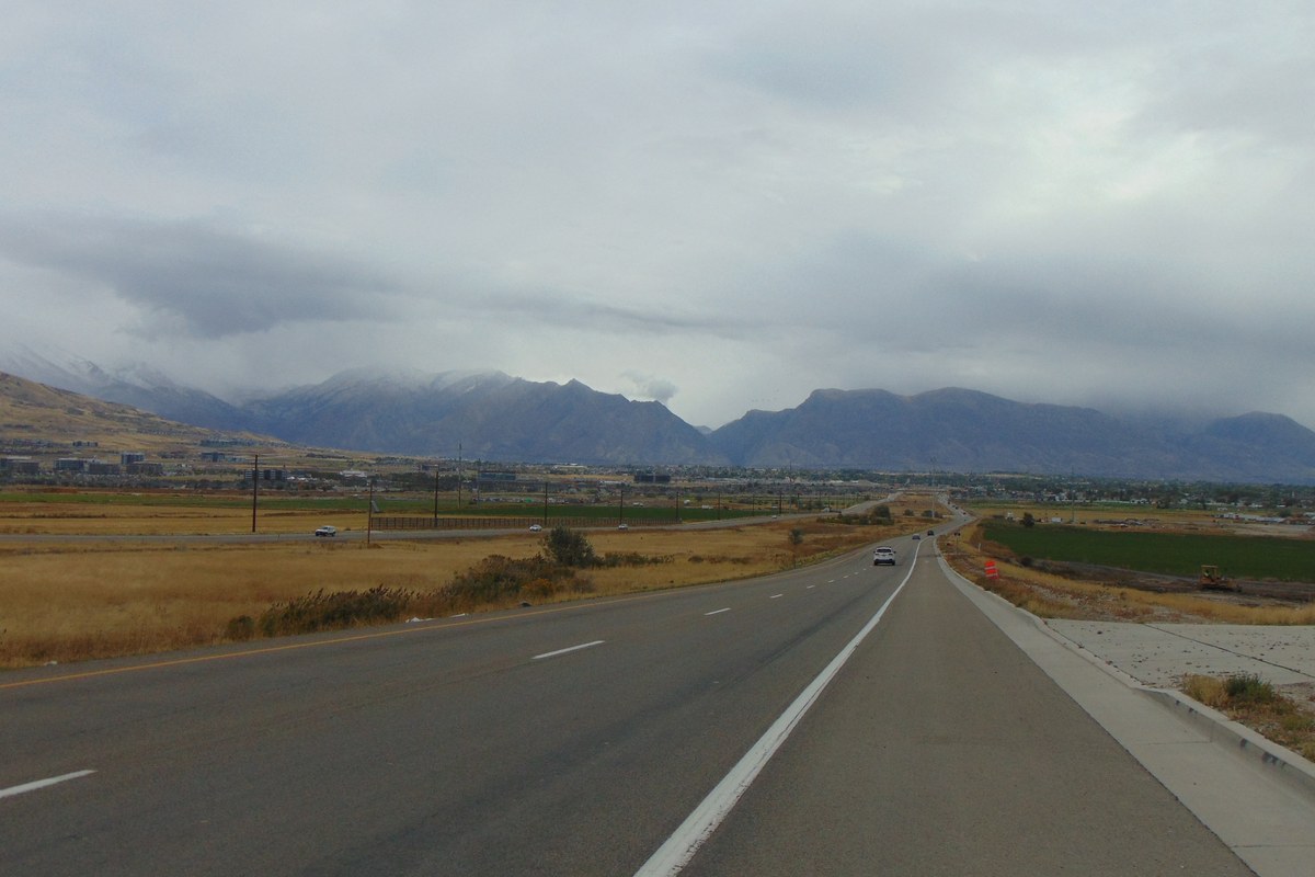 Eastbound 2100 North heading toward Lehi, Utah, in 2016, before freeway construction, with the Wasatch Mountains under clouds