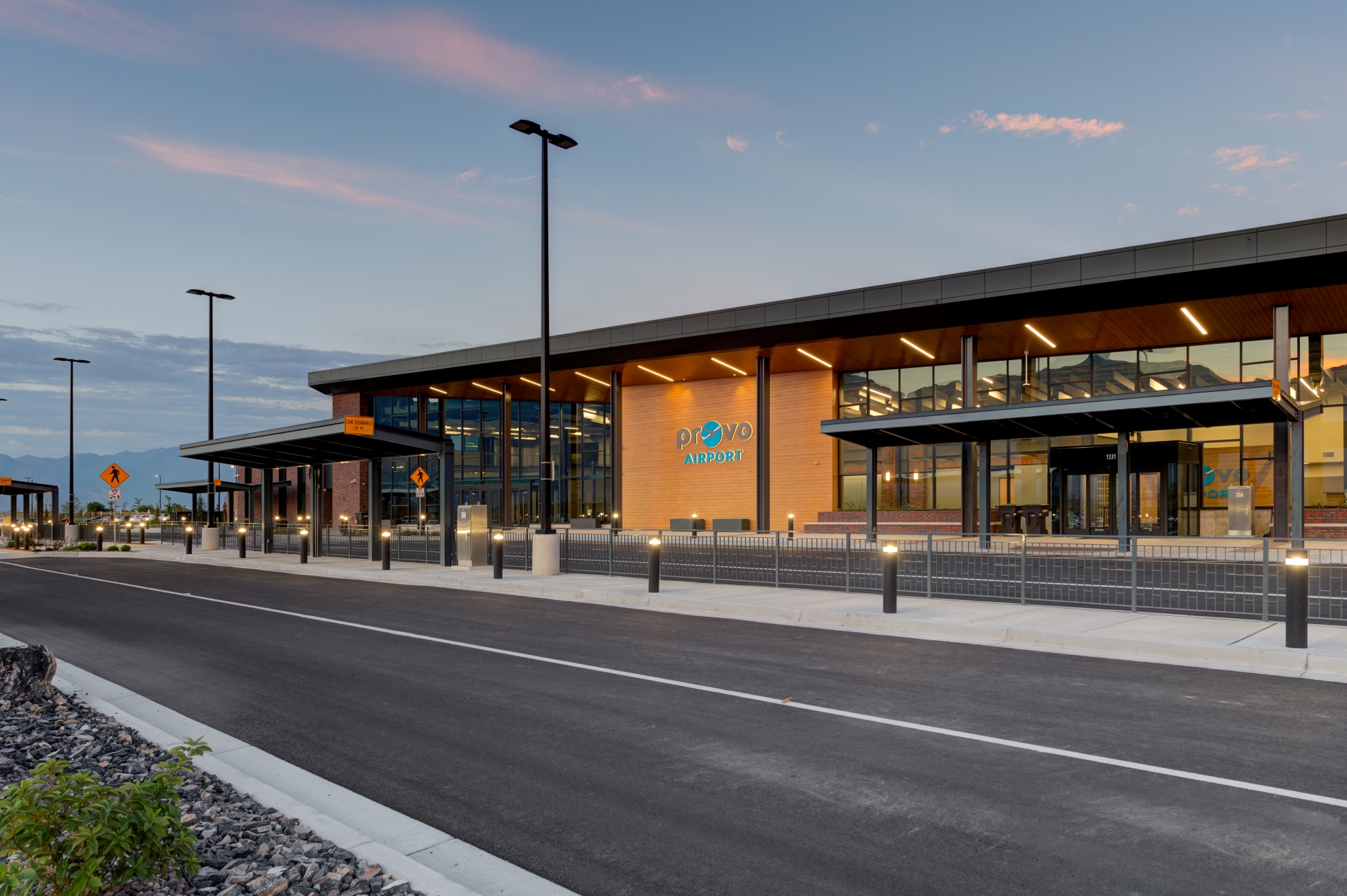 Provo Airport terminal exterior at sunset showcasing modern architecture with glass facade, brick accents, and mountain backdrop - future site of $78 million expansion project that will increase gates from 4 to 10 by 2028, potentially boosting Utah Valley real estate values