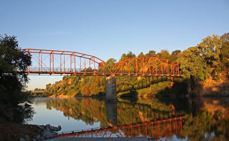Historic Fair Oaks Bridge spanning the American River in Sacramento County, California, surrounded by scenic nature and walking trails.