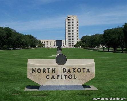 North Dakota State Capitol building in Bismarck, a tall Art Deco tower and landmark on the capitol grounds with green lawn and blue sky