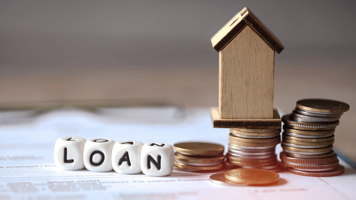 Wooden house model beside stacks of coins and dice spelling “LOAN,” symbolizing FHA home loans, mortgage financing, and real estate investment opportunities in Los Angeles.