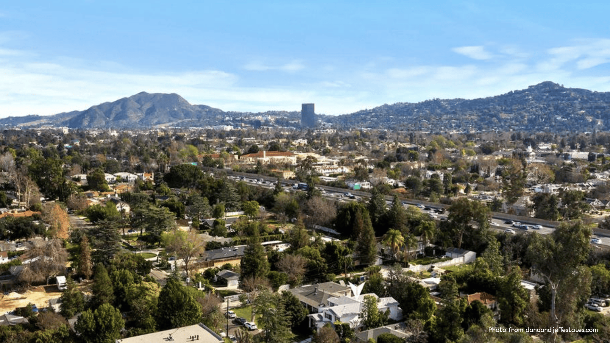 Aerial view of Valley Village in Los Angeles showing residential streets, mature trees, and the 101 Freeway with the Santa Monica Mountains in the background.