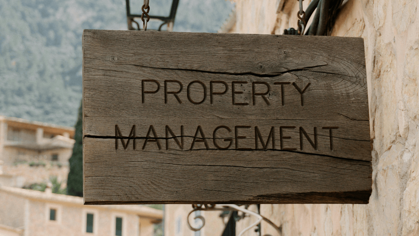 Wooden property management sign hanging outside a building, representing professional real estate management services and rental property operations.