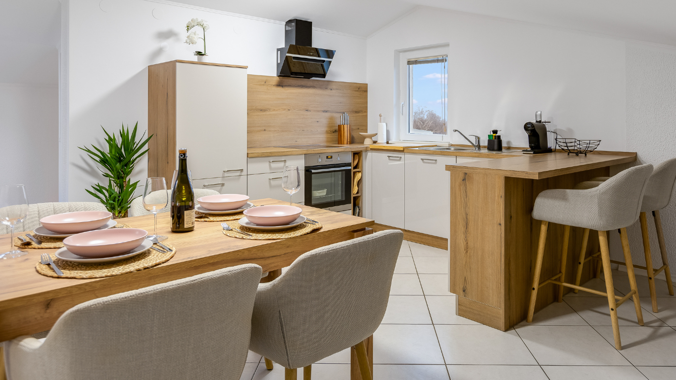 Modern Airbnb kitchen and dining area with natural wood finishes, minimalist design, and bright lighting.