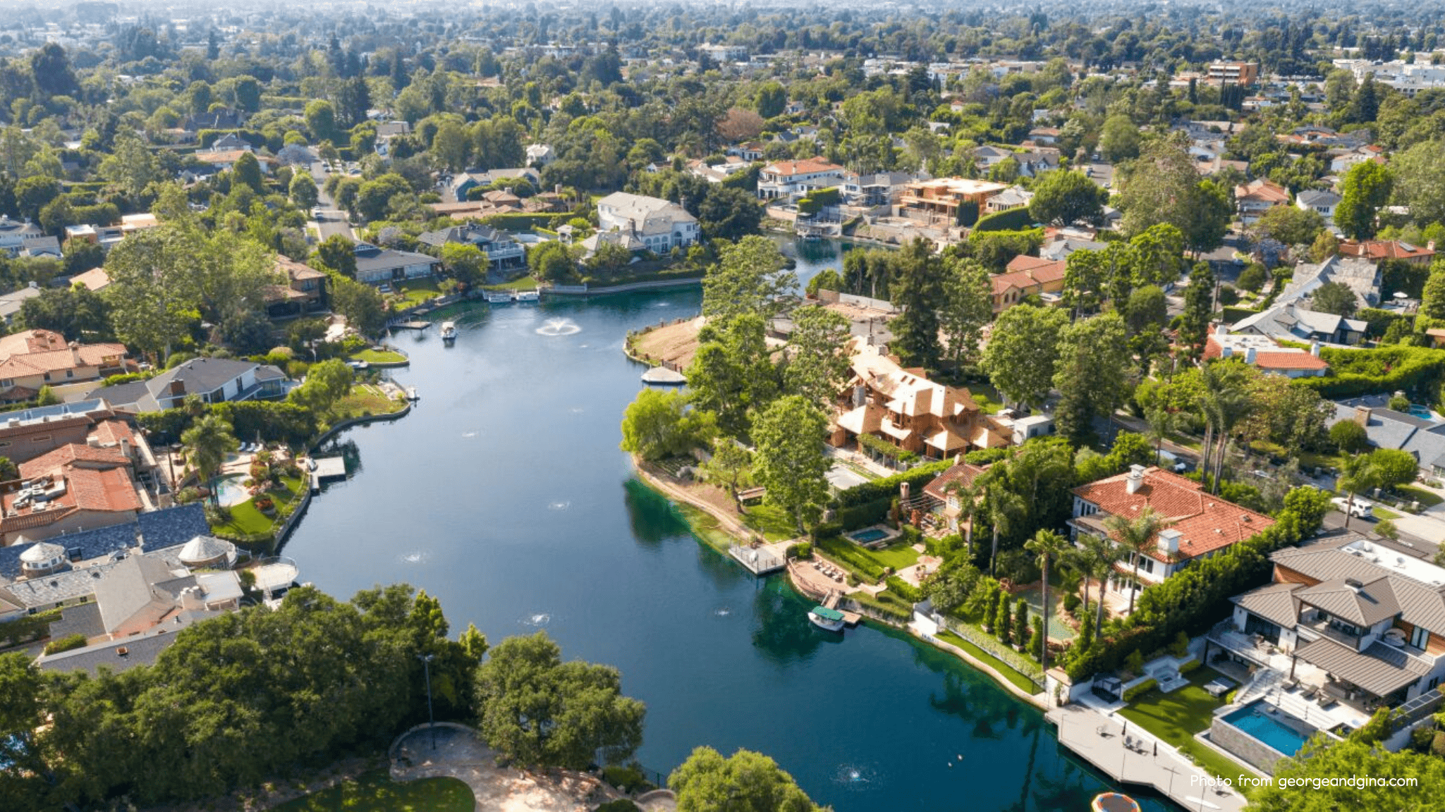 Drone view of Toluca Lake in Los Angeles showcasing waterfront homes, lush greenery, and the residential neighborhood surrounding the scenic lake.