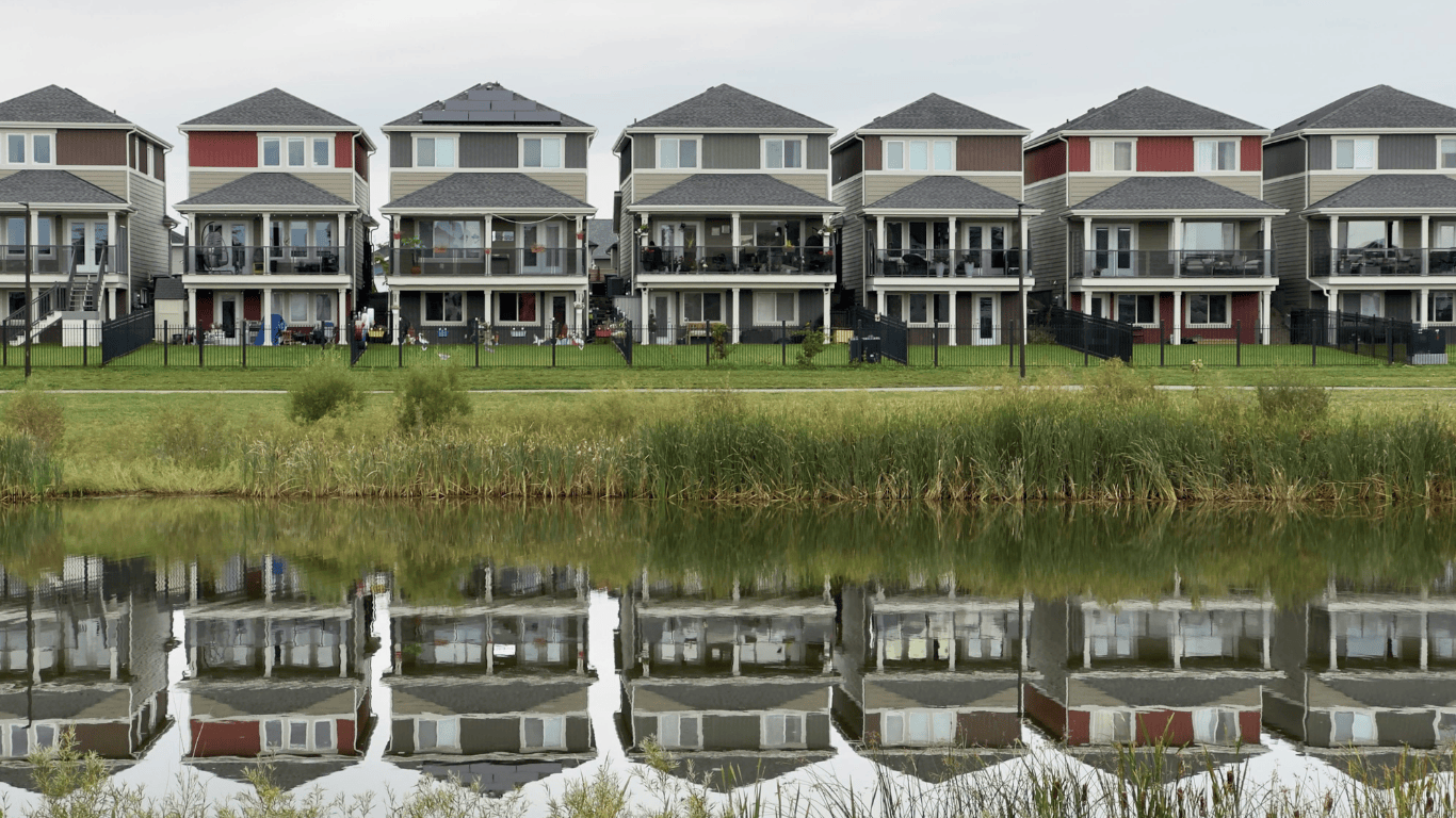 Modern suburban waterfront homes with backyards reflecting on a calm lake, showcasing real estate property design and residential neighborhood living in Los Angeles.