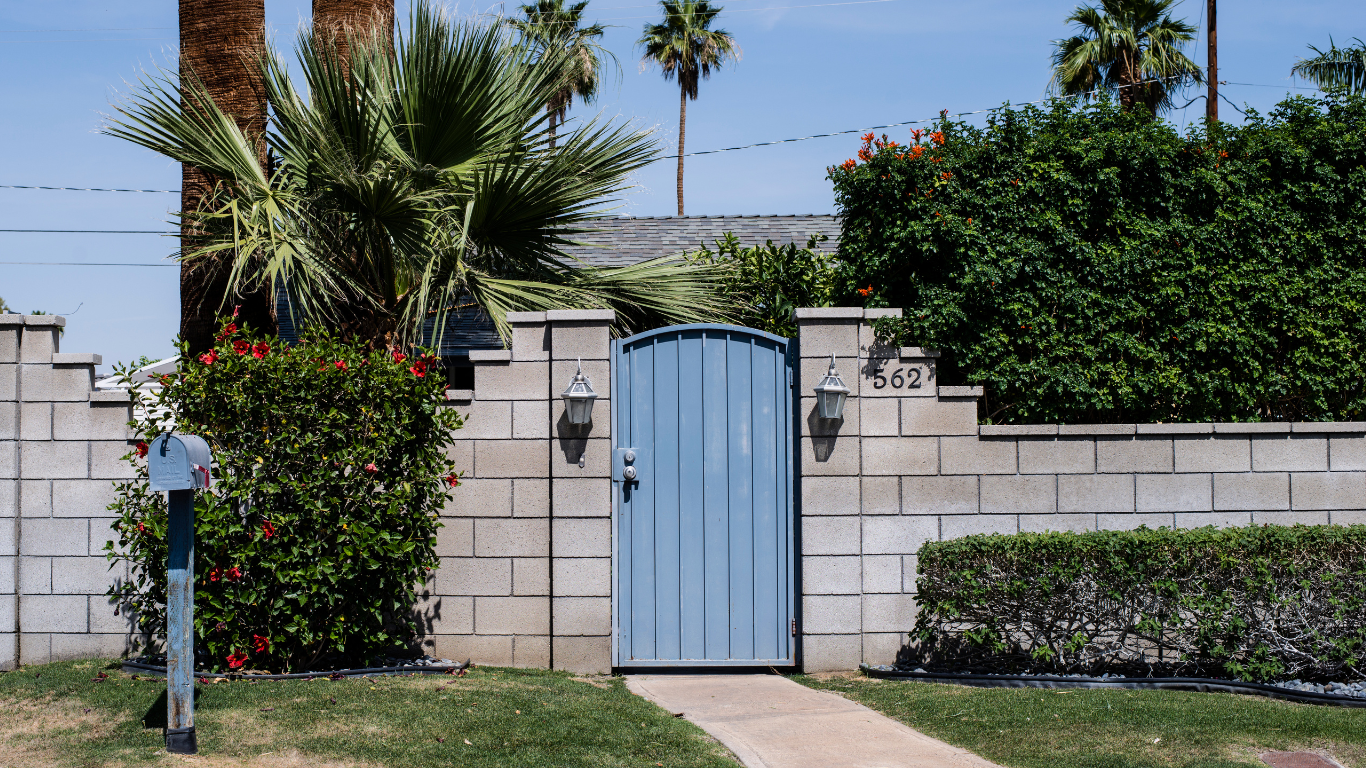Private gated home in Los Angeles with palm trees, landscaped yard, and modern entry gate, showcasing Southern California residential real estate.