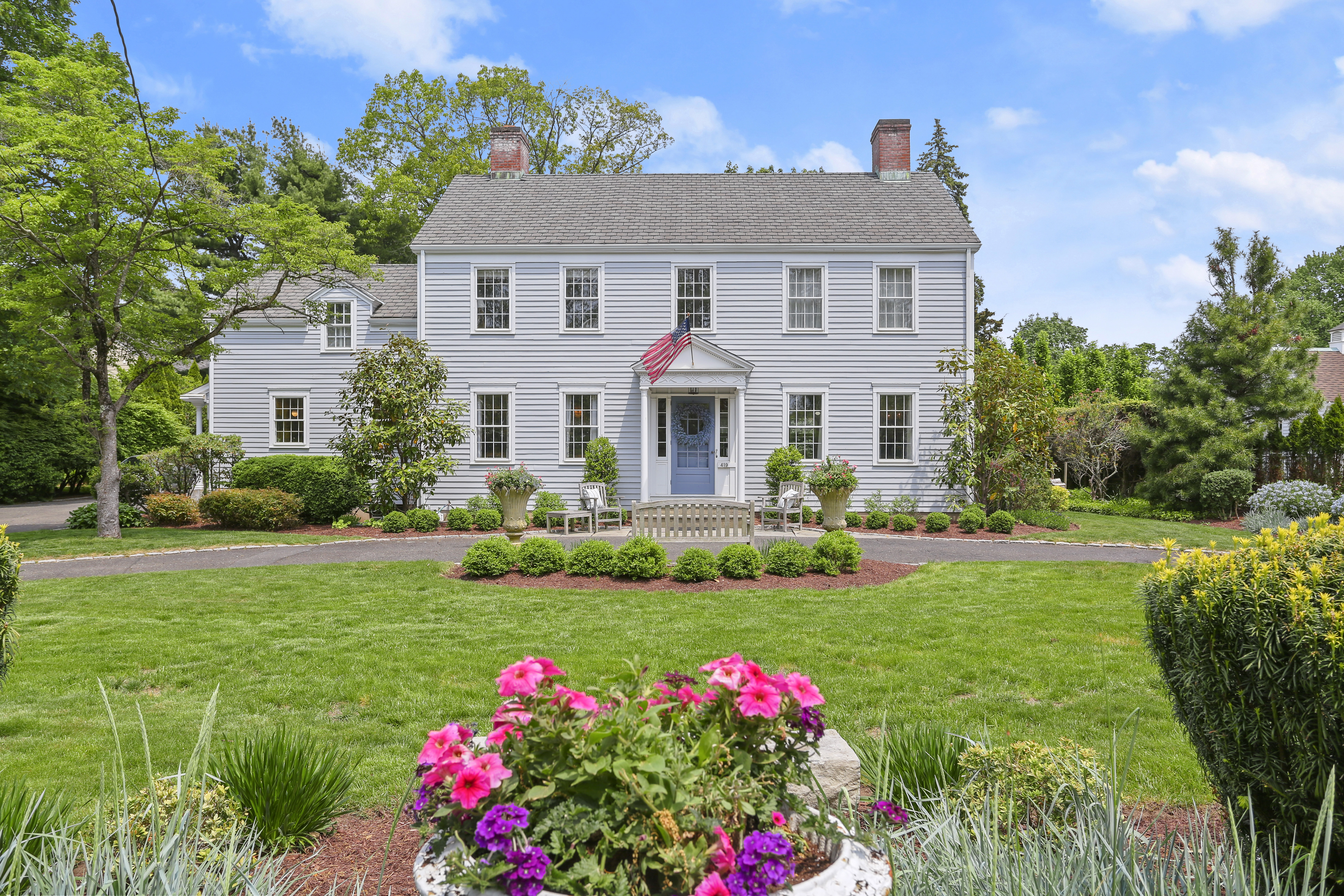 White Colonial with a flowering front garden and green lawn at 419 Beach Road, Fairfield CT