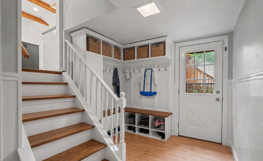 Mudroom with built-in bench, cubbies, and hooks beside the staircase at 163 Windsor Rd, Fairfield CT
