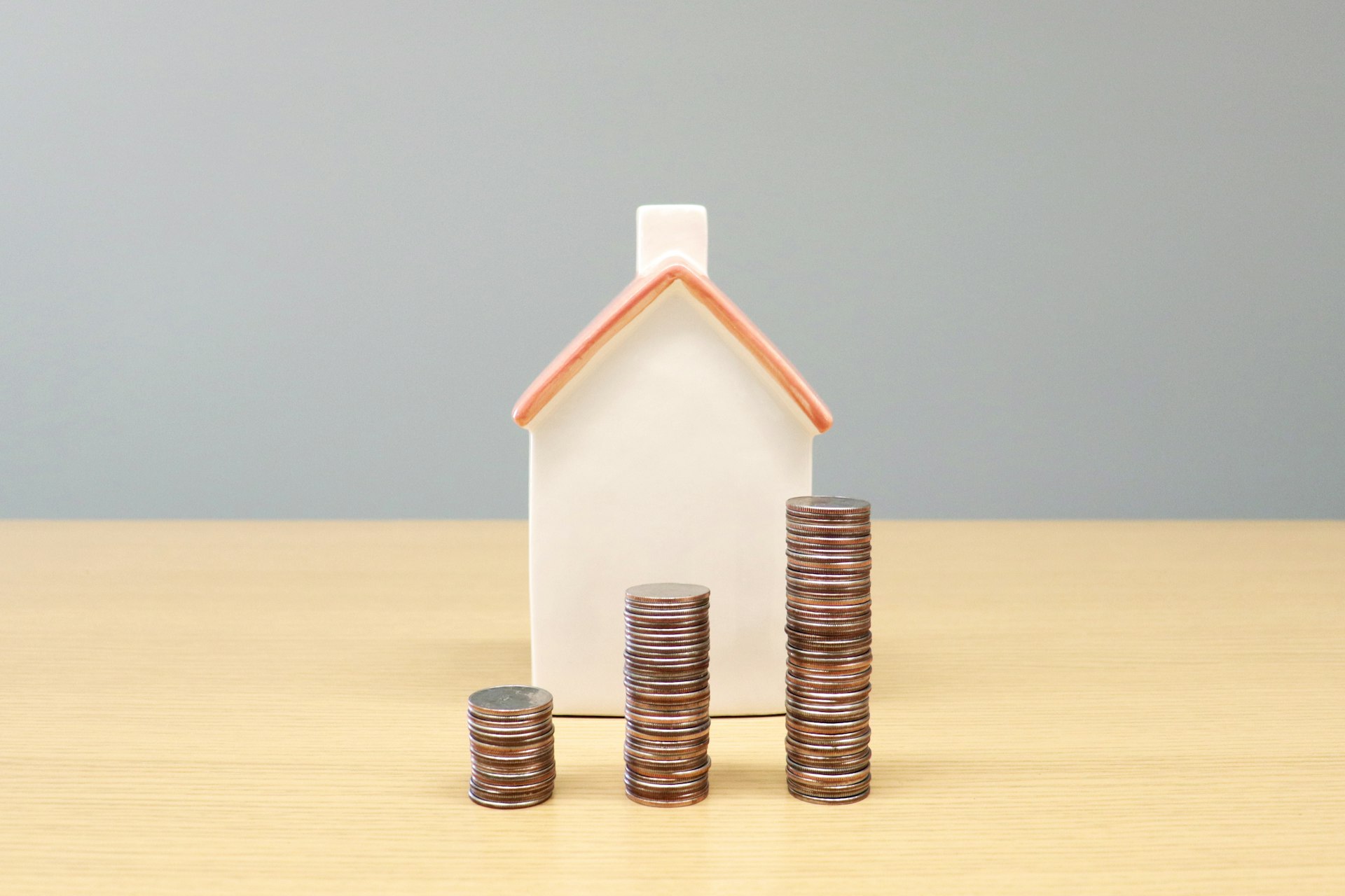 Model house beside rising stacks of coins representing property investment