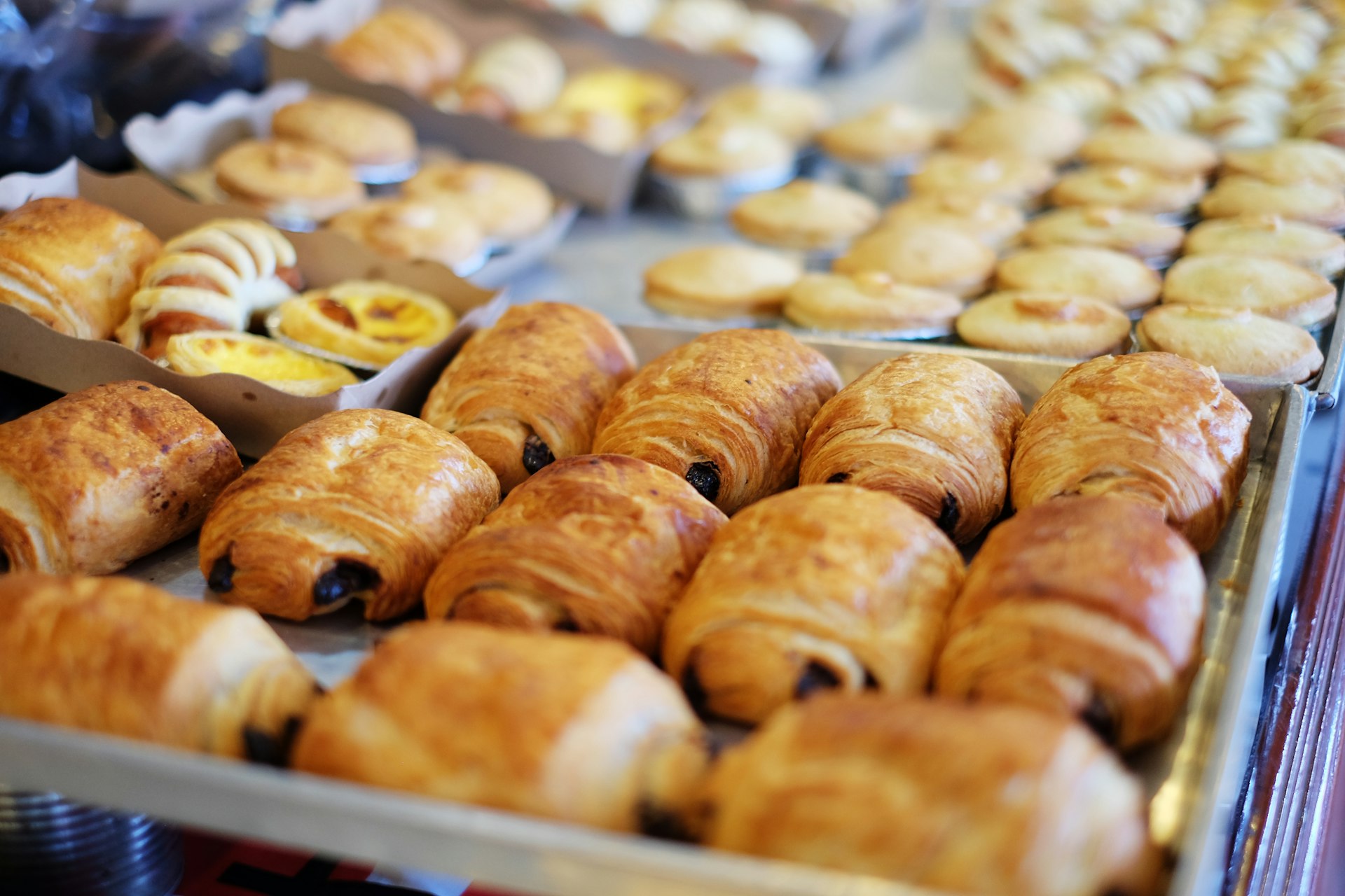 Trays of croissants, pain au chocolat and pastries in a bakery case