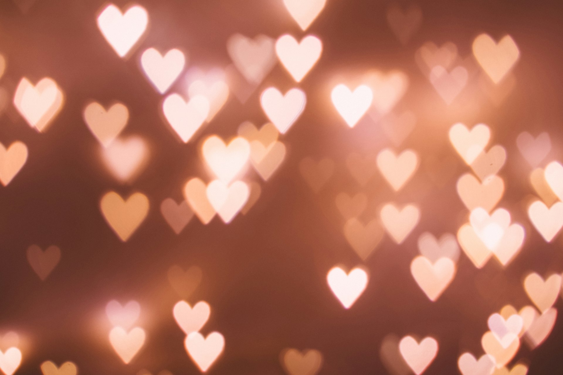 Warm bokeh heart-shaped lights on a soft golden background