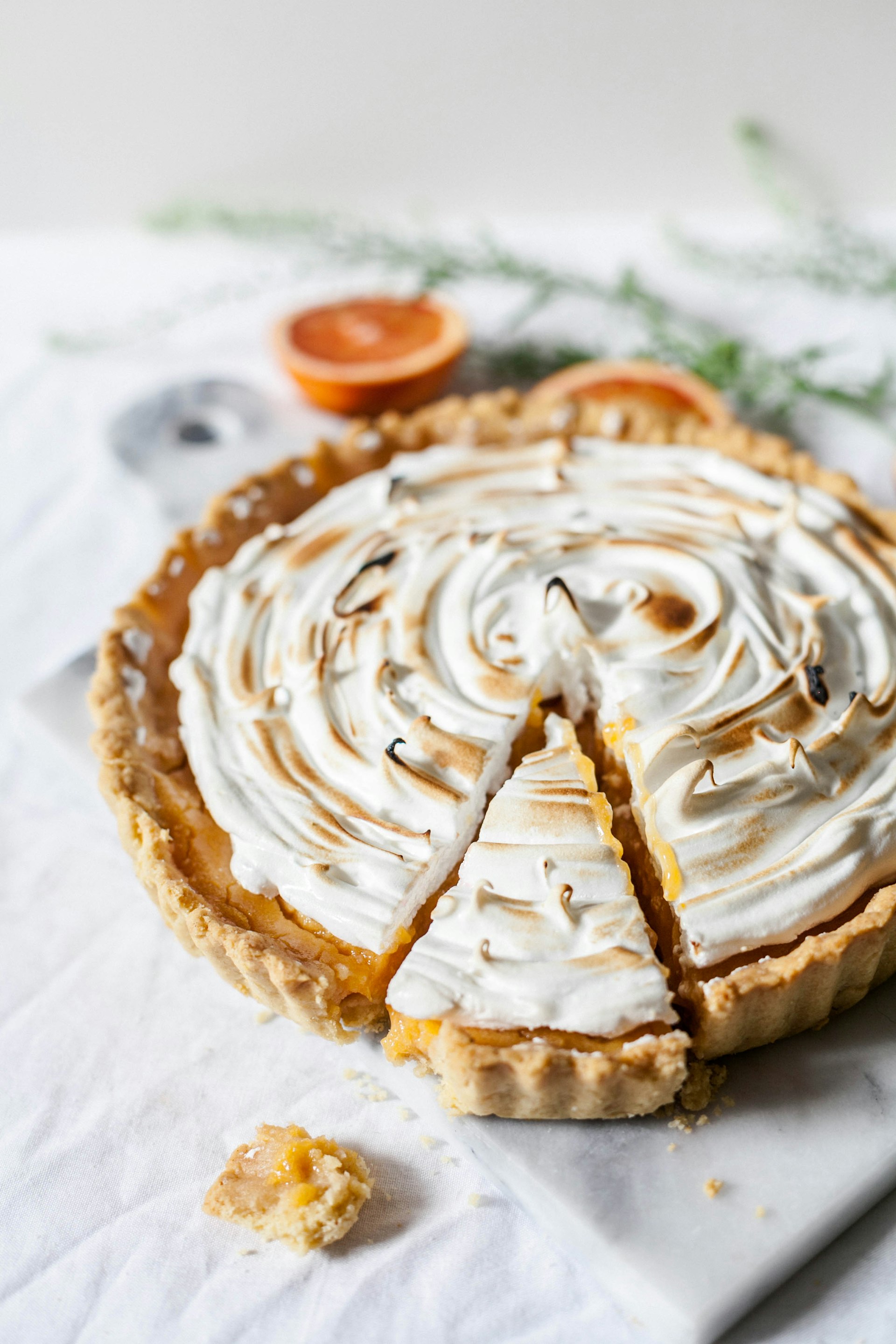 Toasted meringue-topped pie on a marble counter with one slice cut