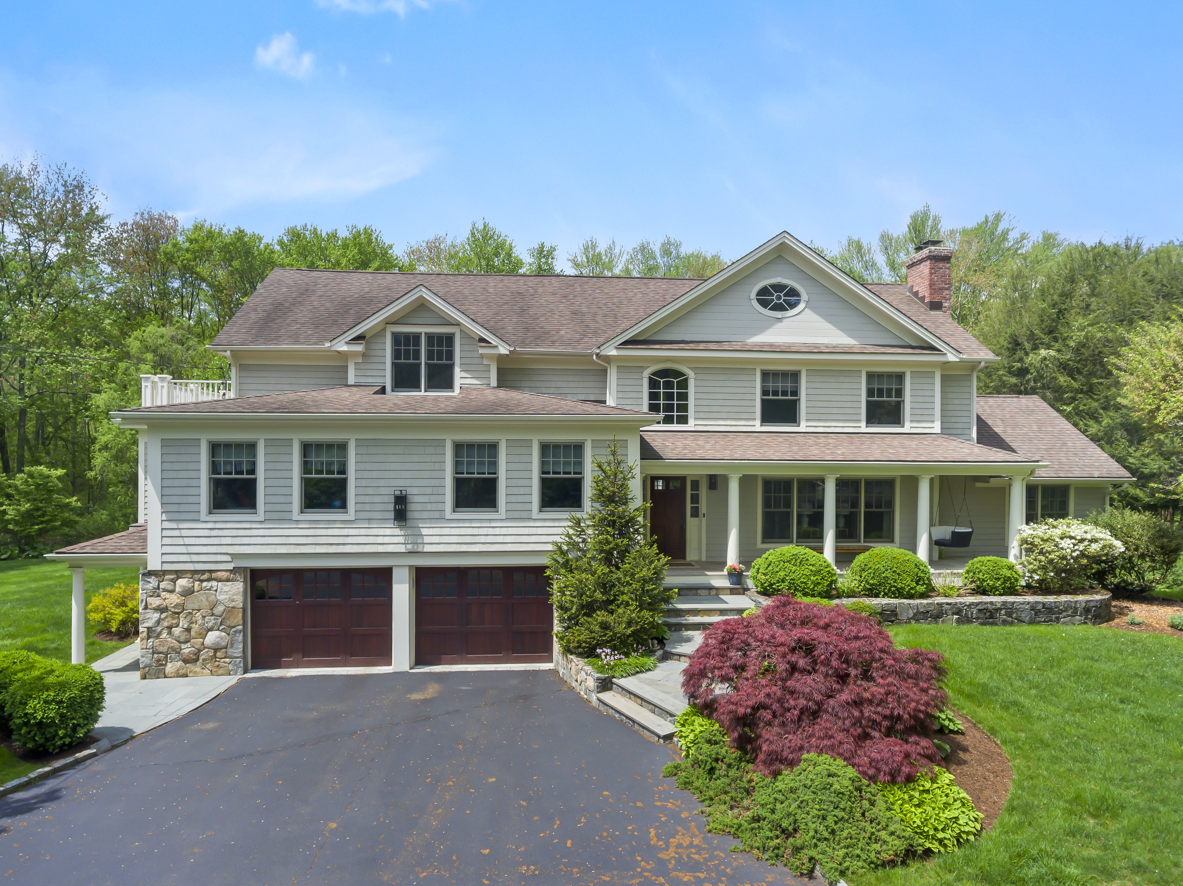 Cream-colored Colonial with an attached two-car garage and mature landscaping at 180 Merwins Lane, Fairfield CT