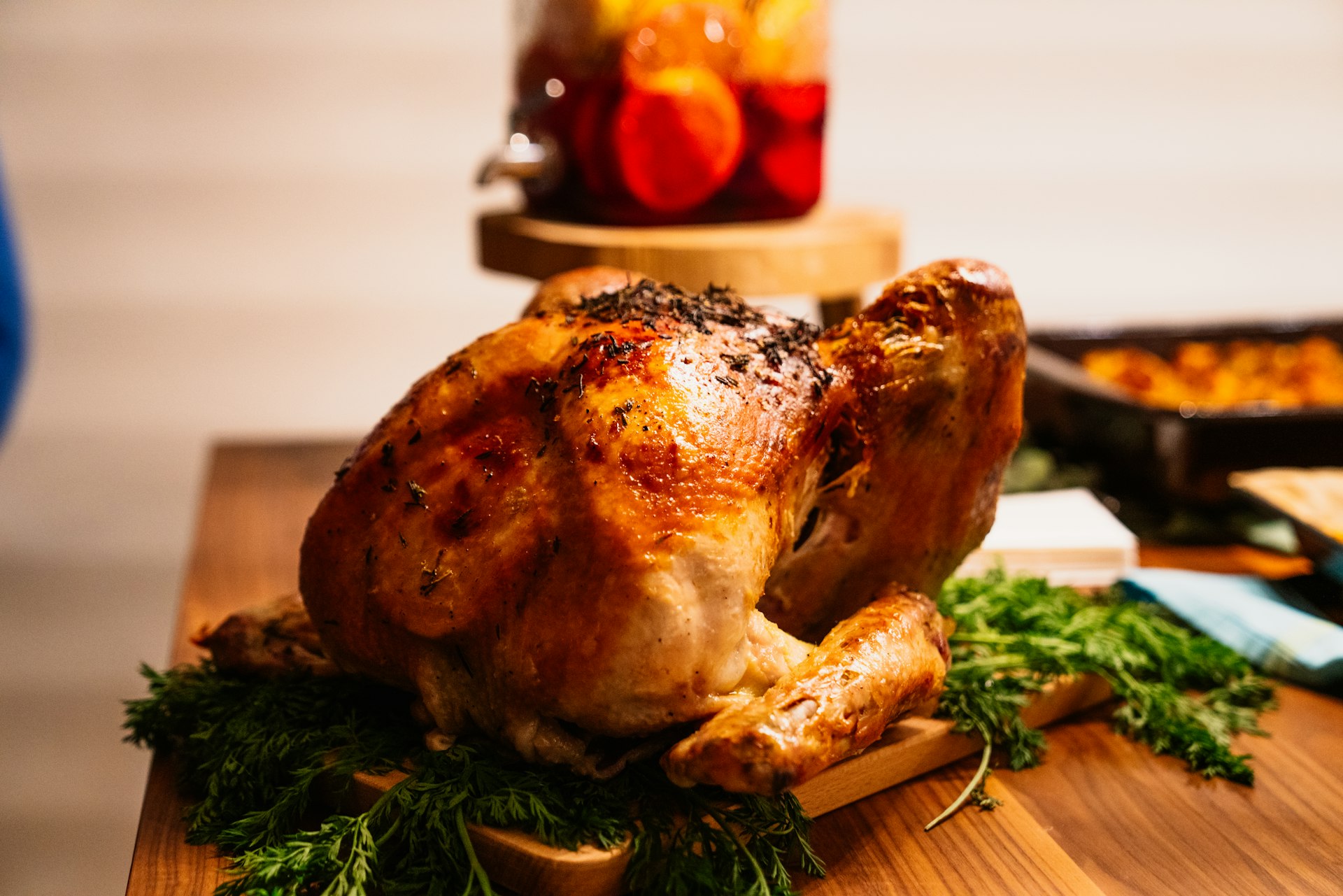 Roast turkey on a wooden board surrounded by herbs and side dishes