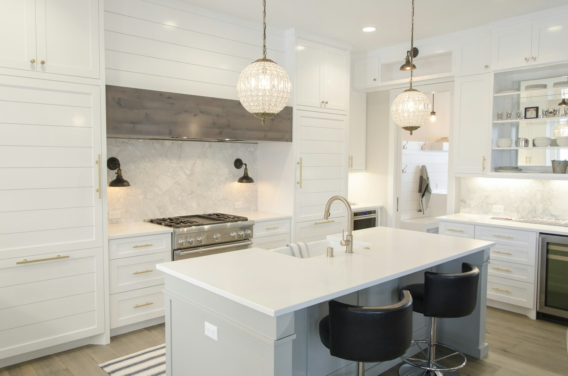 White kitchen with marble island, glass pendants and range hood
