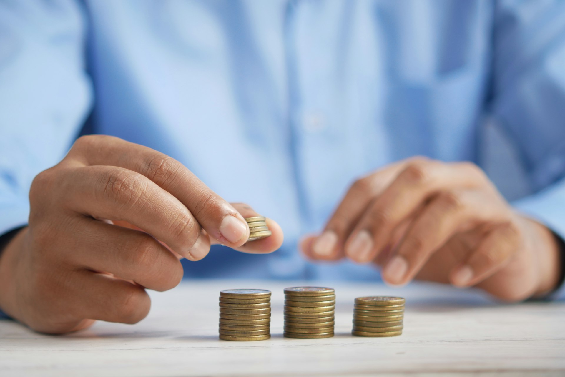 Hands stacking coins in growing piles on a table