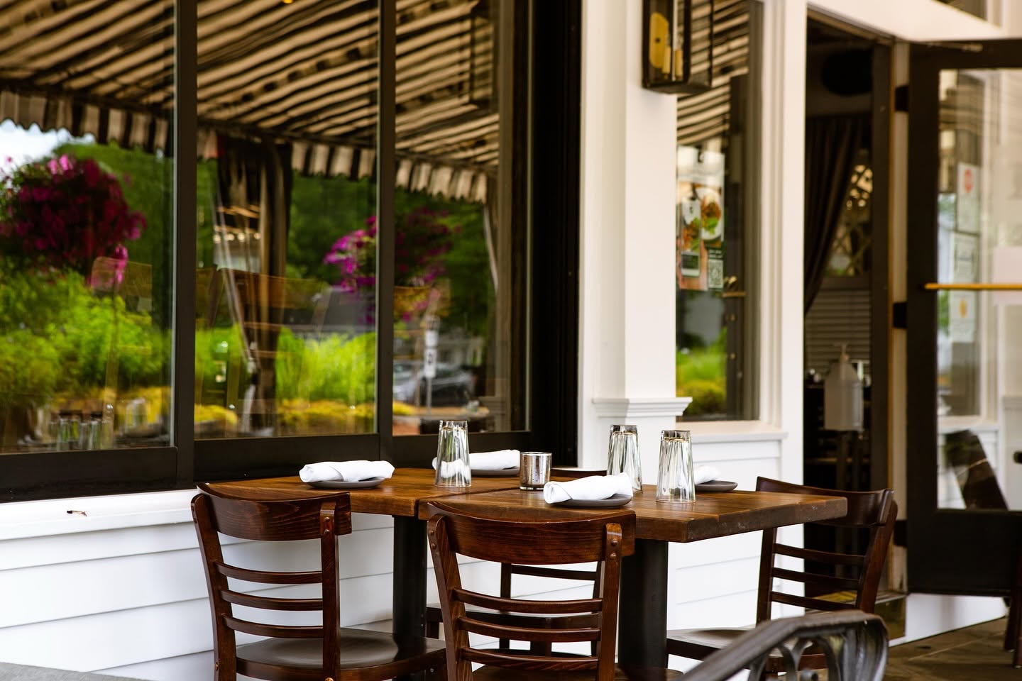 A set table on a covered patio under a black-and-white striped awning in Fairfield, Connecticut