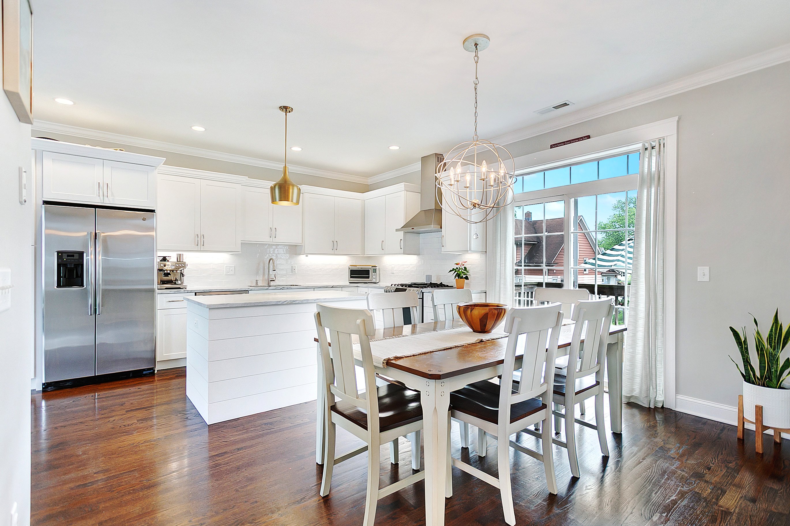 Bright white kitchen with a center island, pendant lighting and dining area at 157 Brentwood Avenue, Fairfield CT