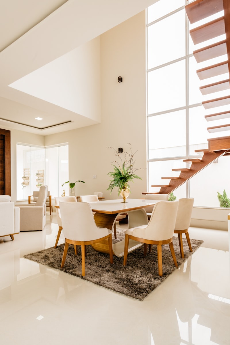 Bright dining area with light wood table and open staircase behind