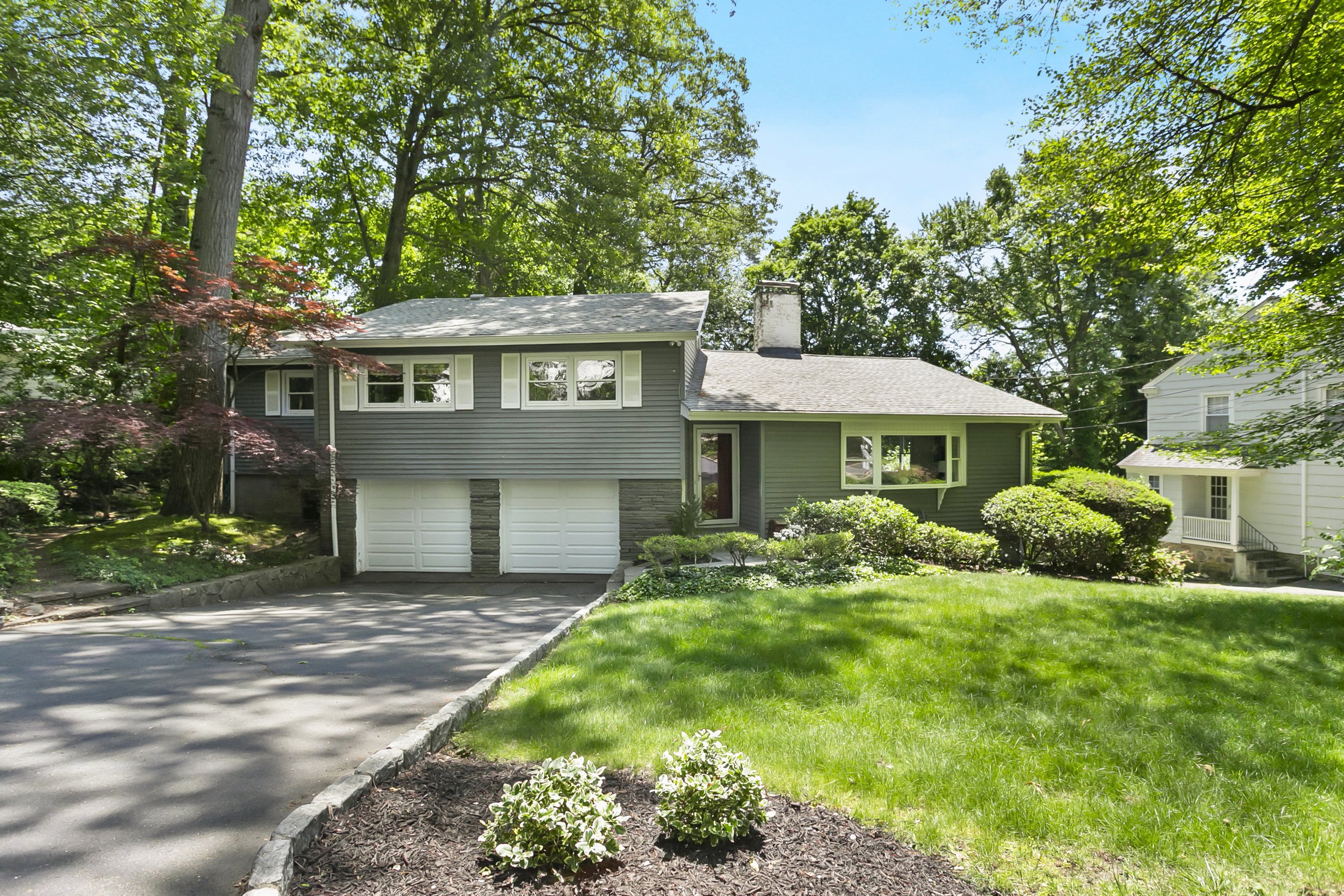 Green split-level home with an attached garage and mature trees at 219 Jackman Avenue, Fairfield CT