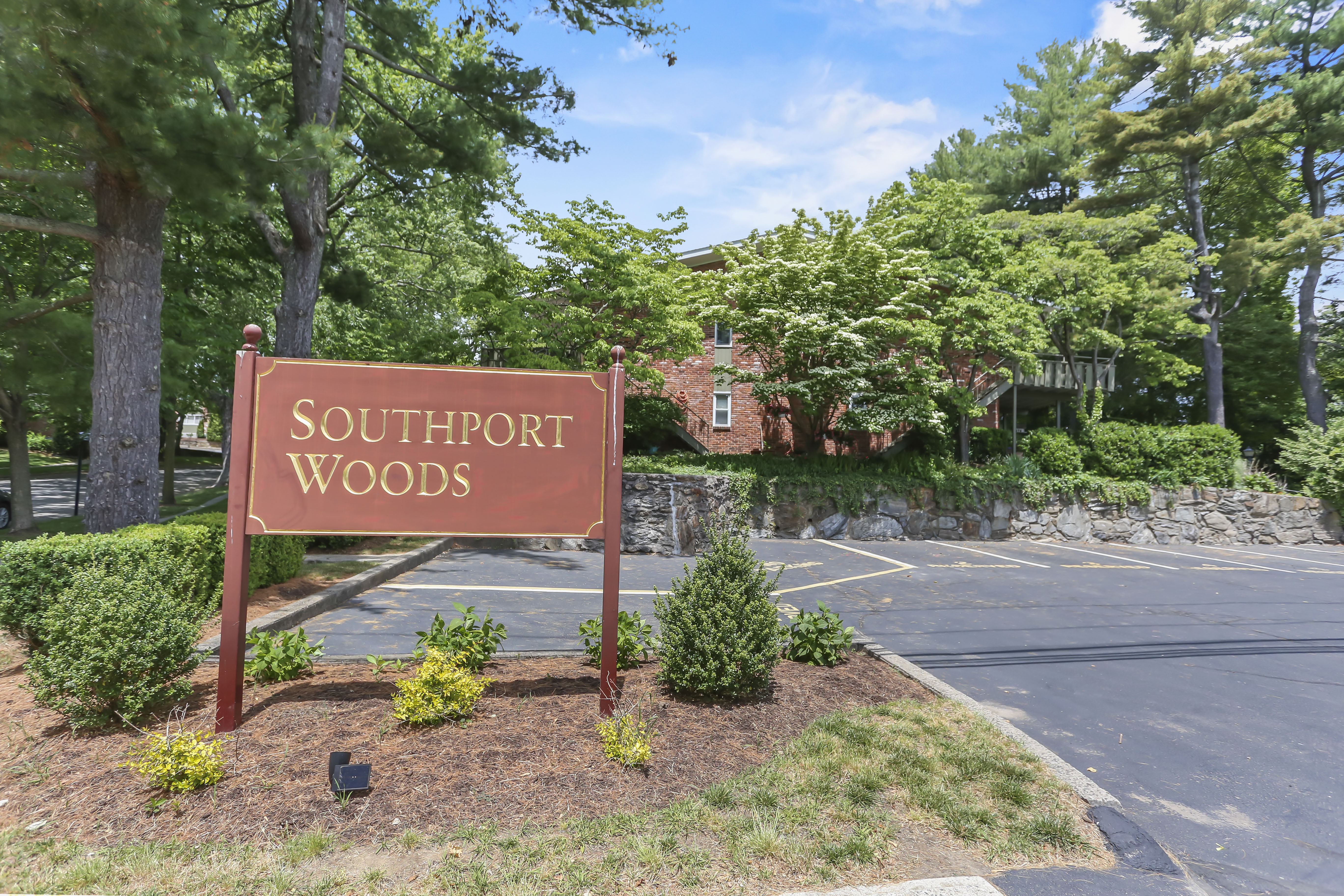 Wooden Southport Woods community entrance sign framed by landscaping and mature trees in Southport CT