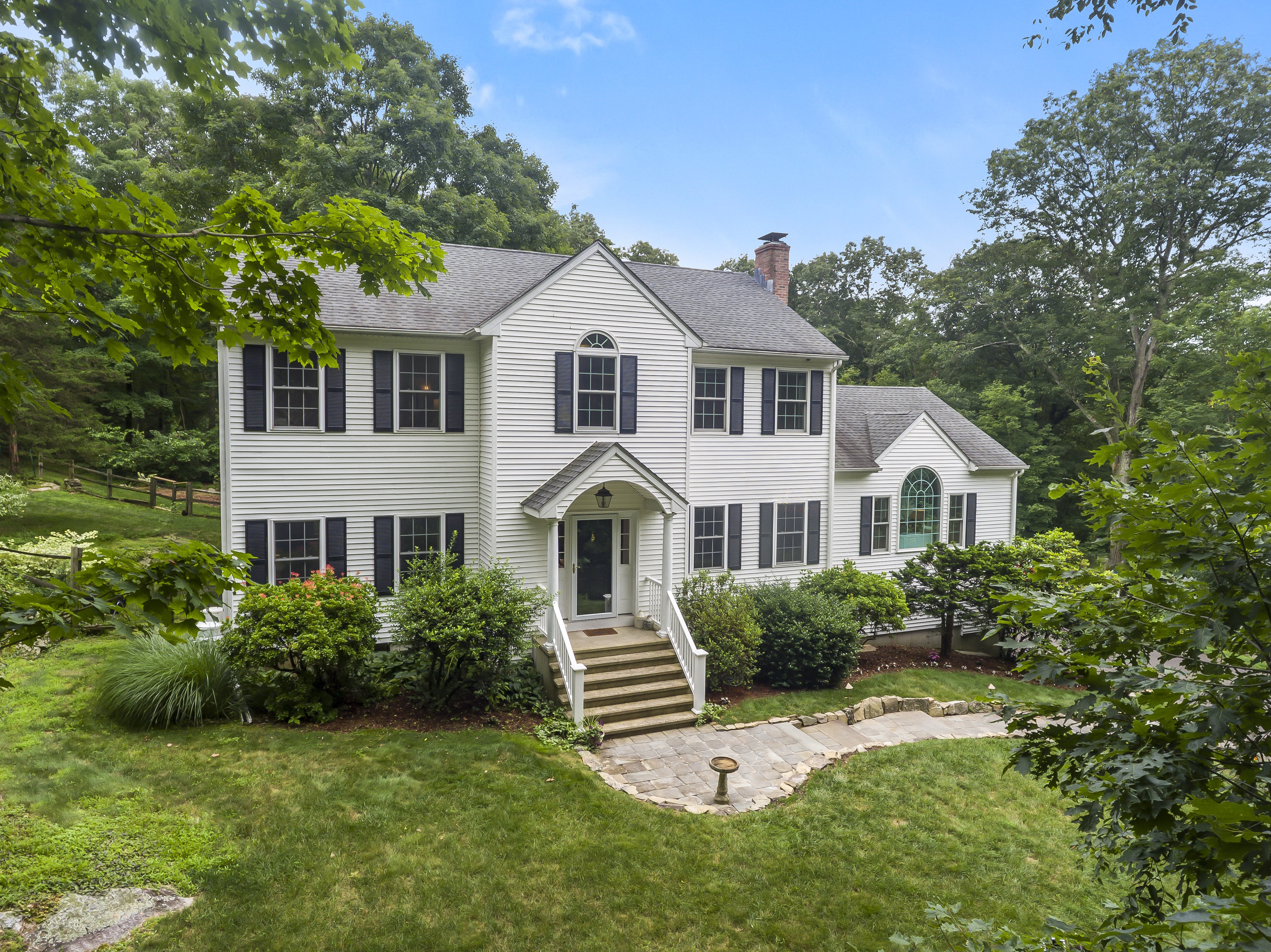 White Center Hall Colonial with black shutters on a wooded lot at 10 Applegate Lane, Monroe CT, recently sold