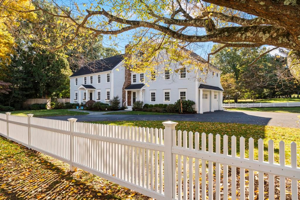 Front exterior of 10 Twin Brooks Lane, a white Colonial behind a picket fence in Fairfield