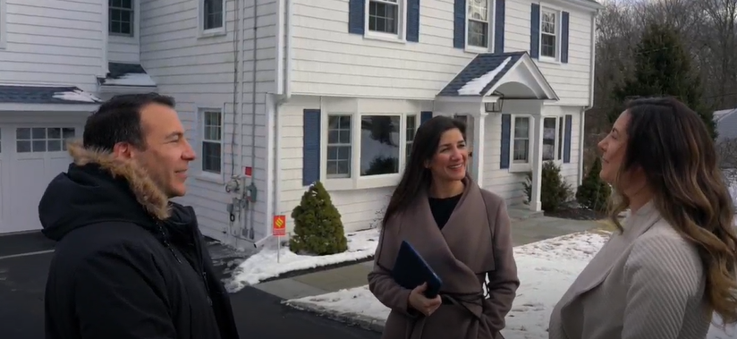 Shoshana Snyder talking with clients outside a colonial home on a winter day
