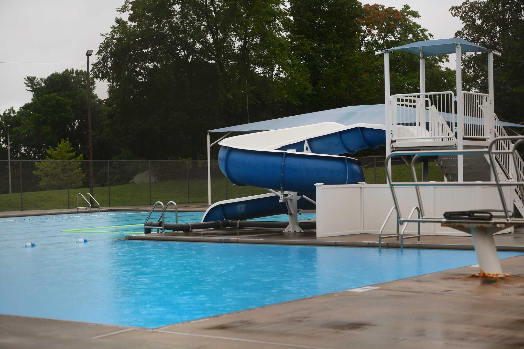 Outdoor community pool with a blue water slide, lifeguard chair and diving board in Trumbull CT