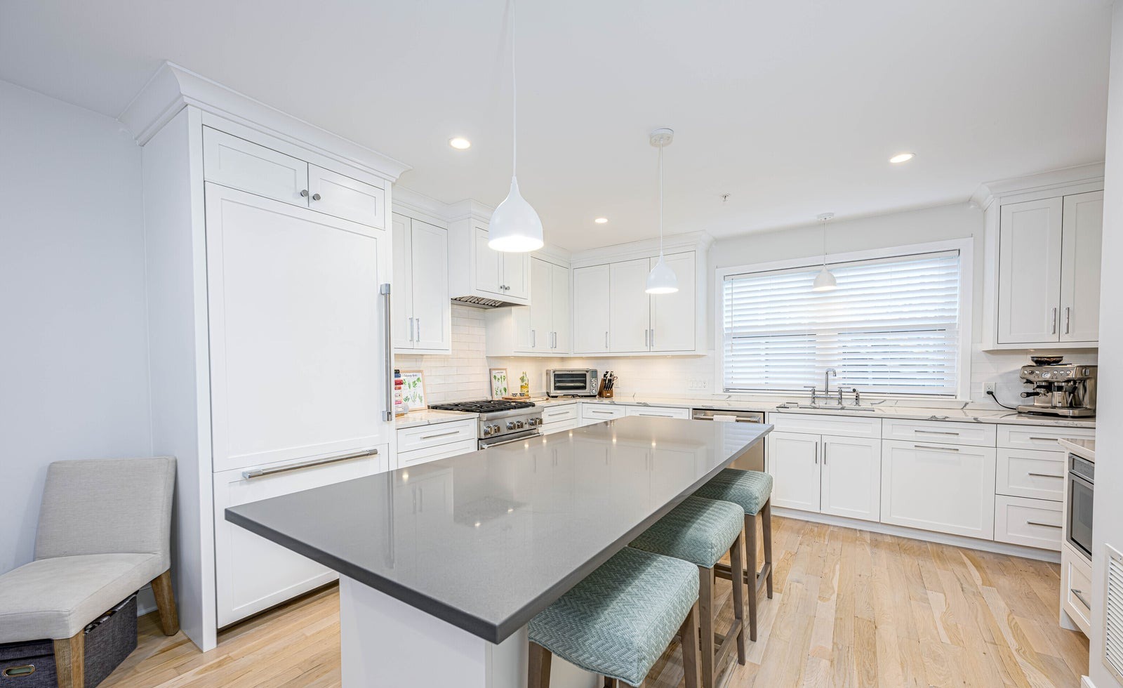 Modern white kitchen with an oversized dark stone island, bar seating and stainless Thermador appliances