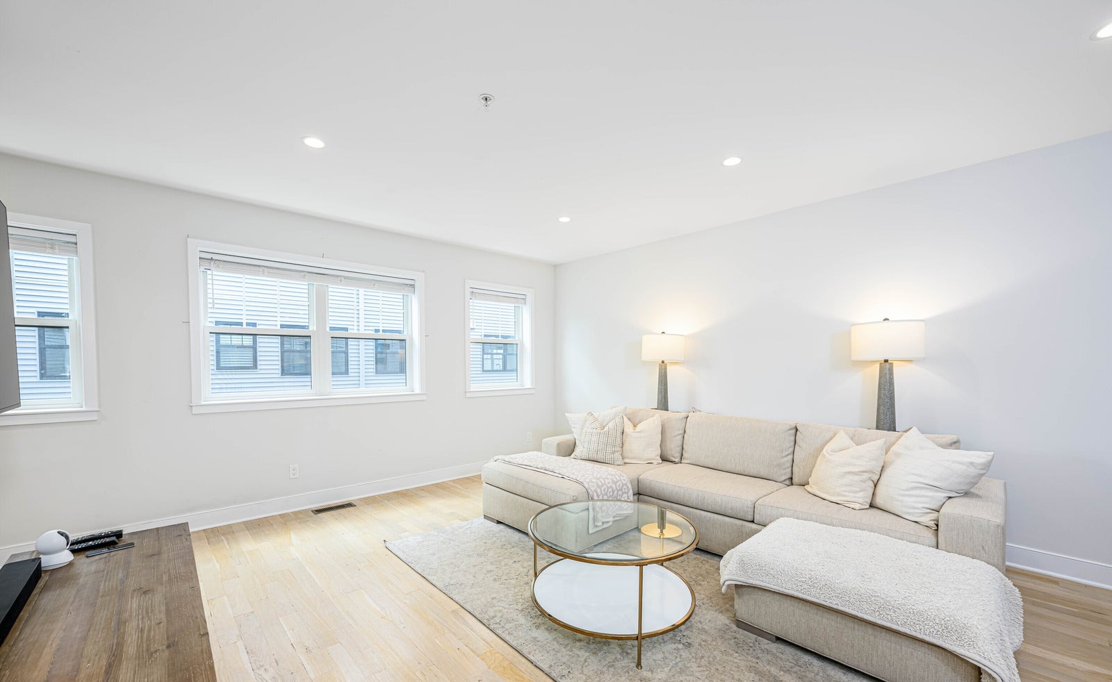 Bright open living room with pale hardwood floors, white walls and large windows