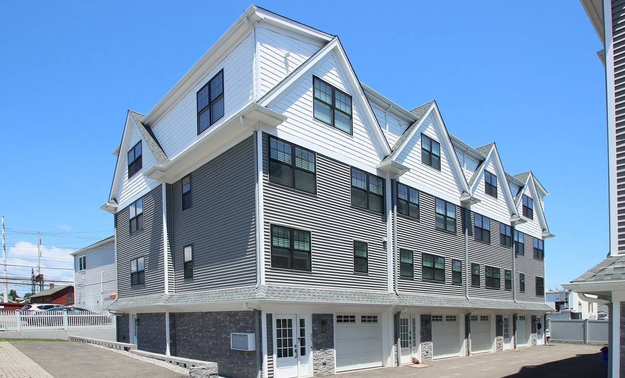 Row of modern gray-and-white shingled townhouses with peaked rooflines and black-framed windows