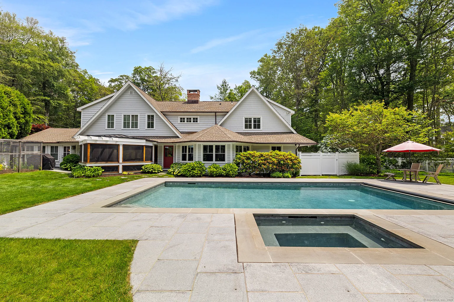 Shingled home with a rear patio, in-ground pool and spa on a lawn at 9 Woodside Lane, Westport CT