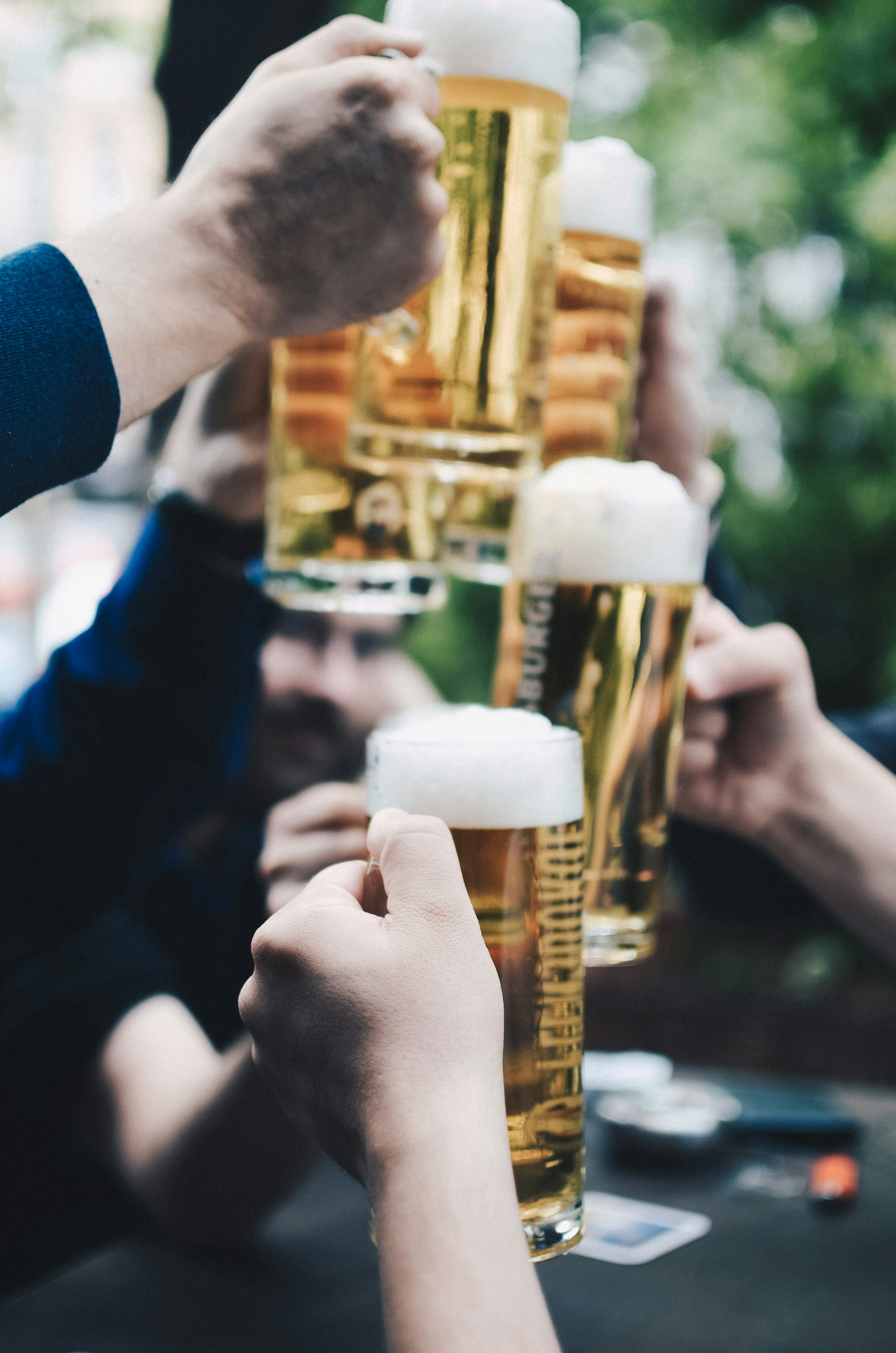 Friends clinking tall glasses of beer at an outdoor celebration