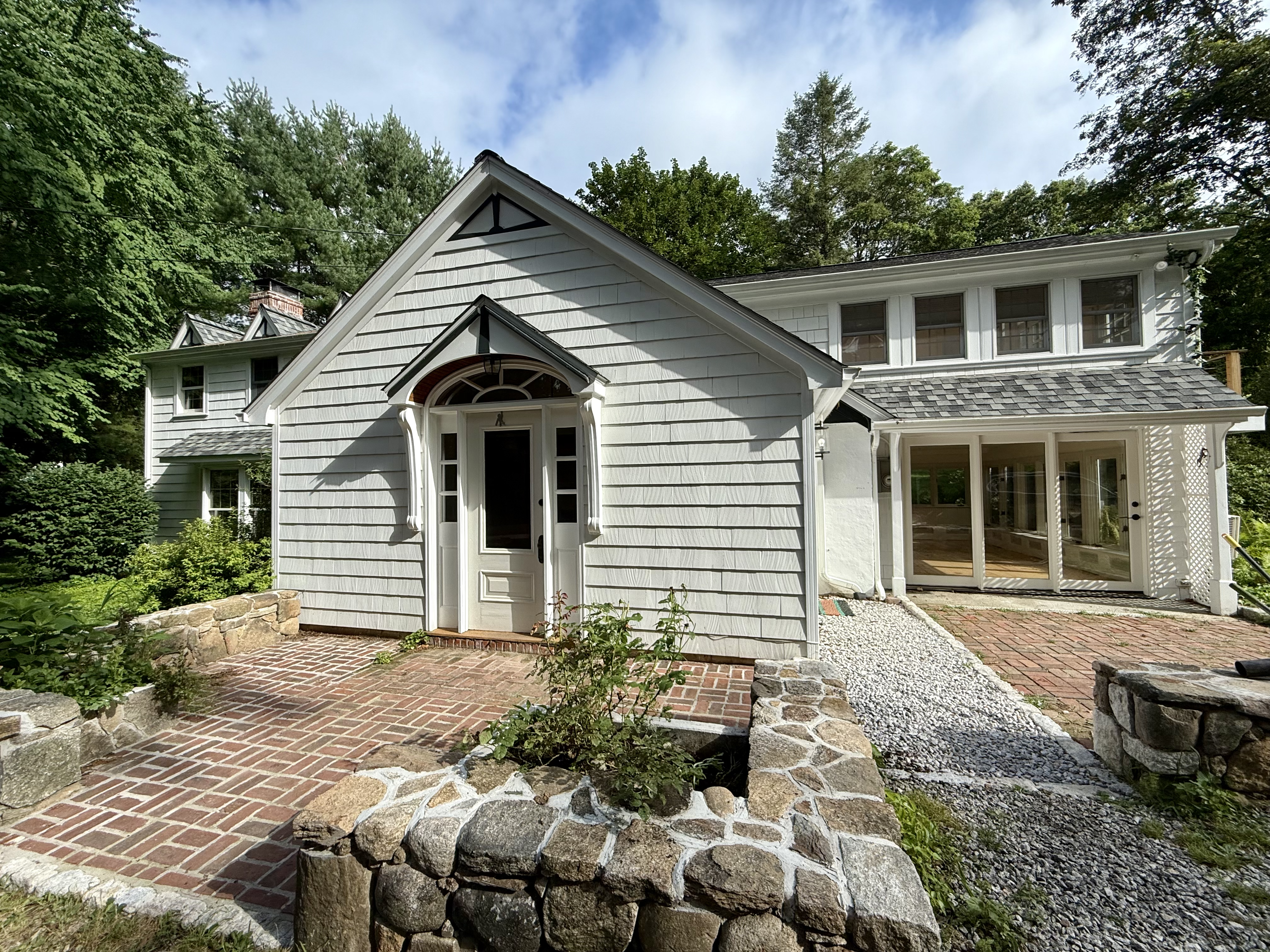 White country cottage with a peaked entry porch and stone walkway at 206 Sharp Hill Road, Wilton CT