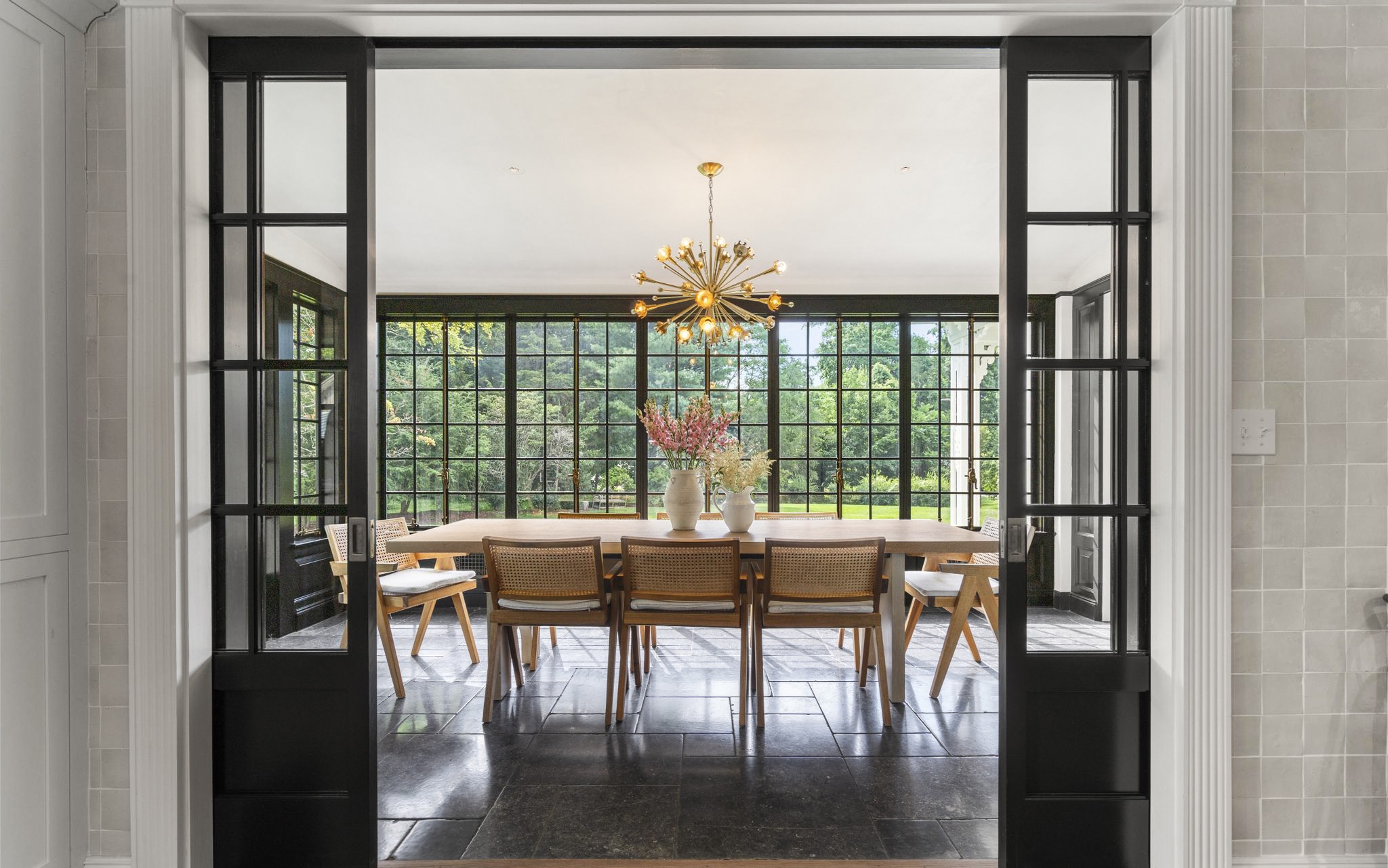 Dining area framed by oversized windows overlooking the private grounds at 98 Banks Place, Southport CT
