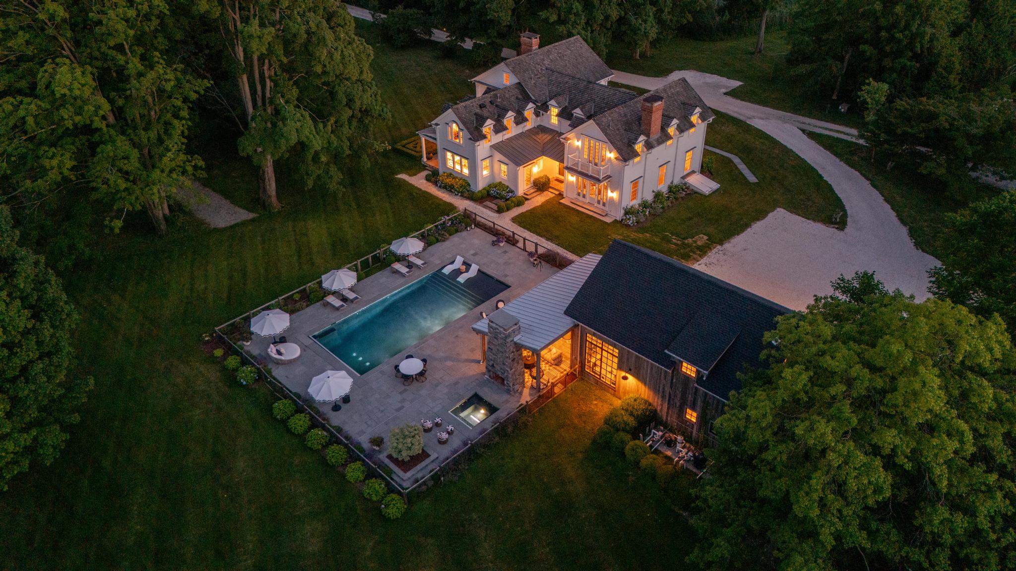 98 Banks Place, an 1830 Greek Revival estate in Southport CT, shown at dusk with the pool and grounds