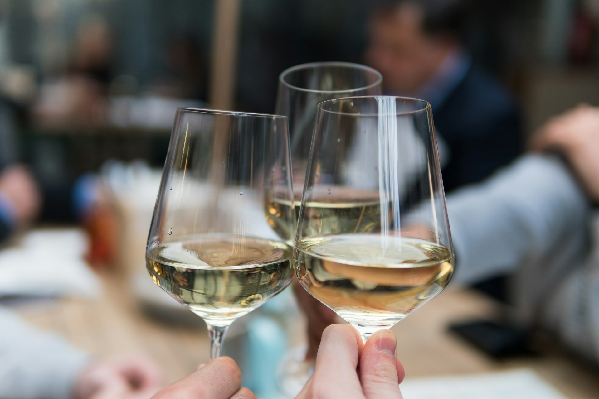 Three glasses of white wine raised in a toast at a Fairfield restaurant bar