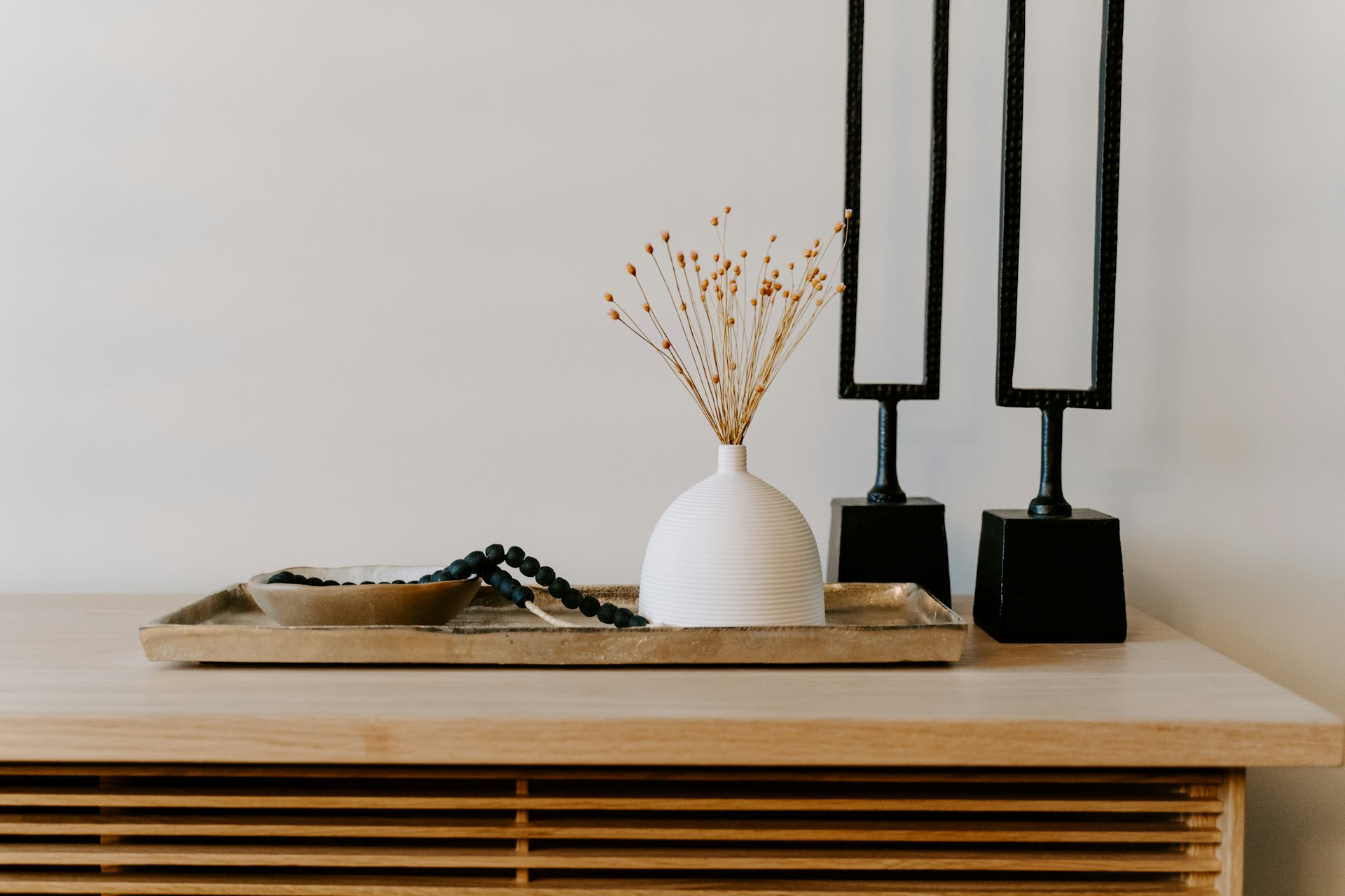 Console table with dried florals in a ceramic vase and black candlesticks