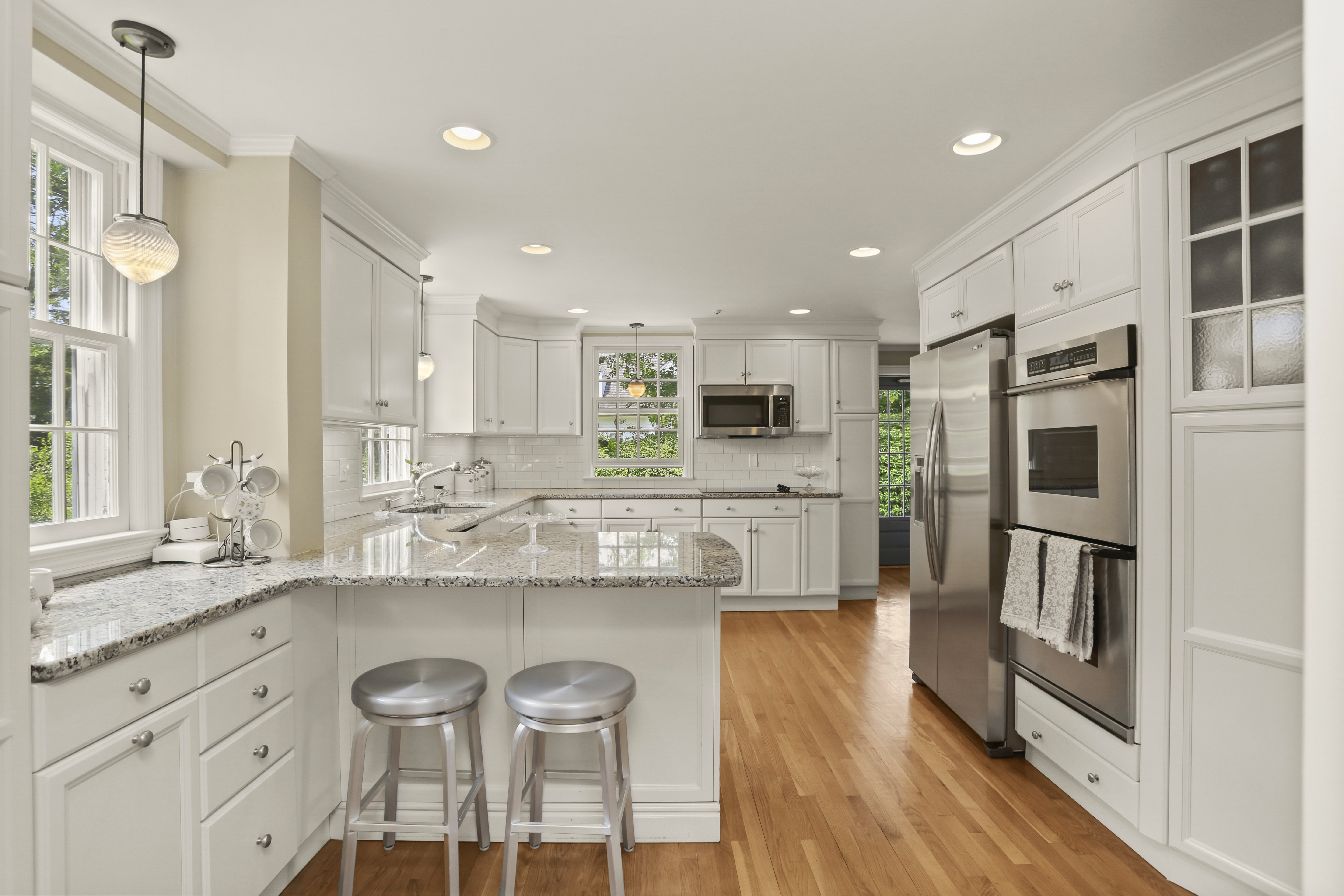 White kitchen with granite counters, a peninsula with stools and stainless double ovens in a Fairfield Beach home