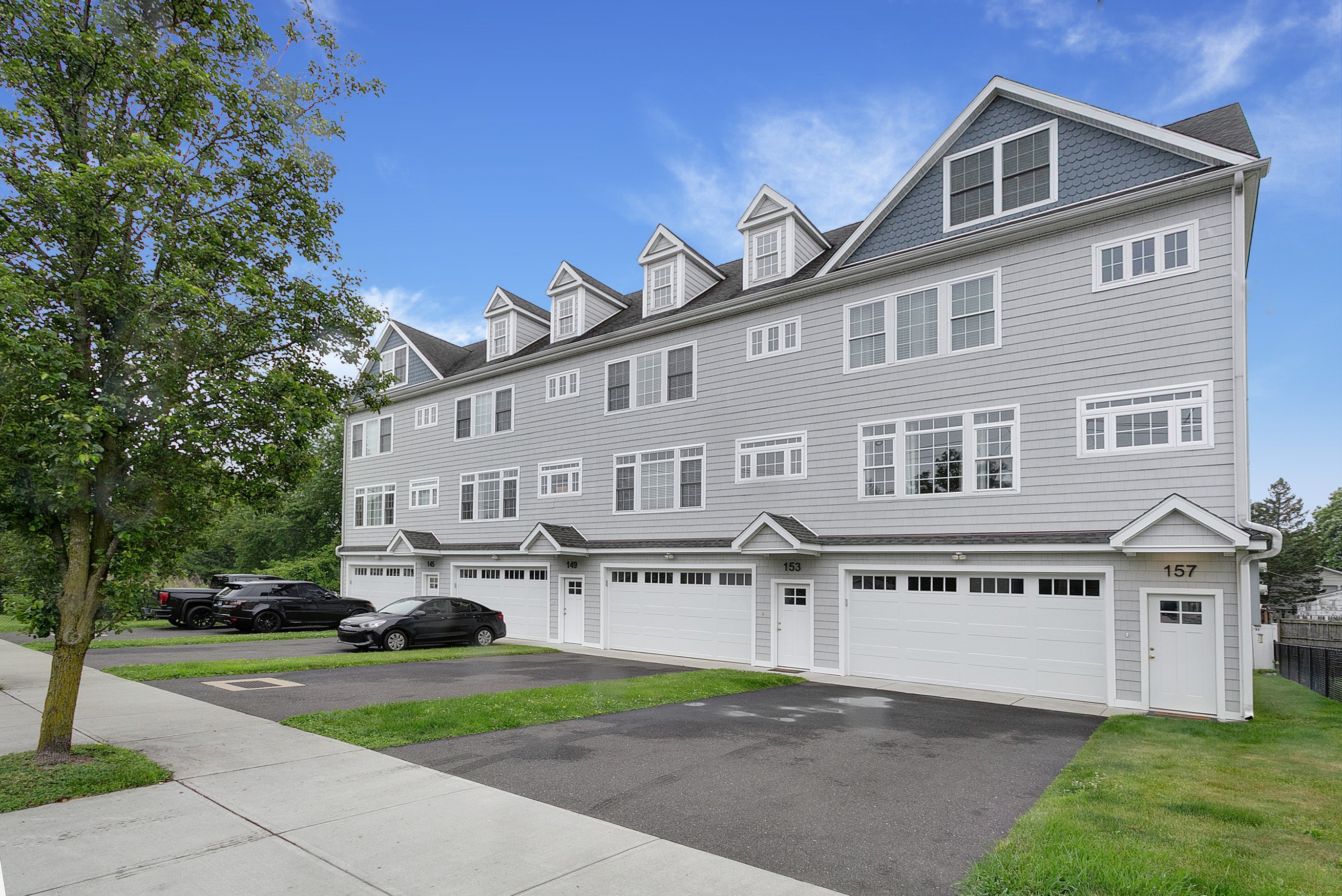 Gray townhouse row with attached garages and dormers at 157 Brentwood Avenue, Fairfield CT