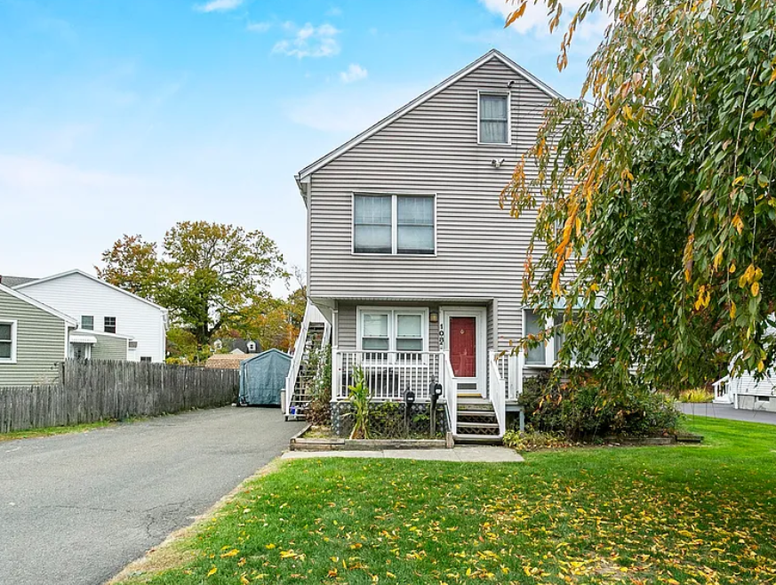 Side view of a two-family home with red front door and driveway in Fairfield, CT