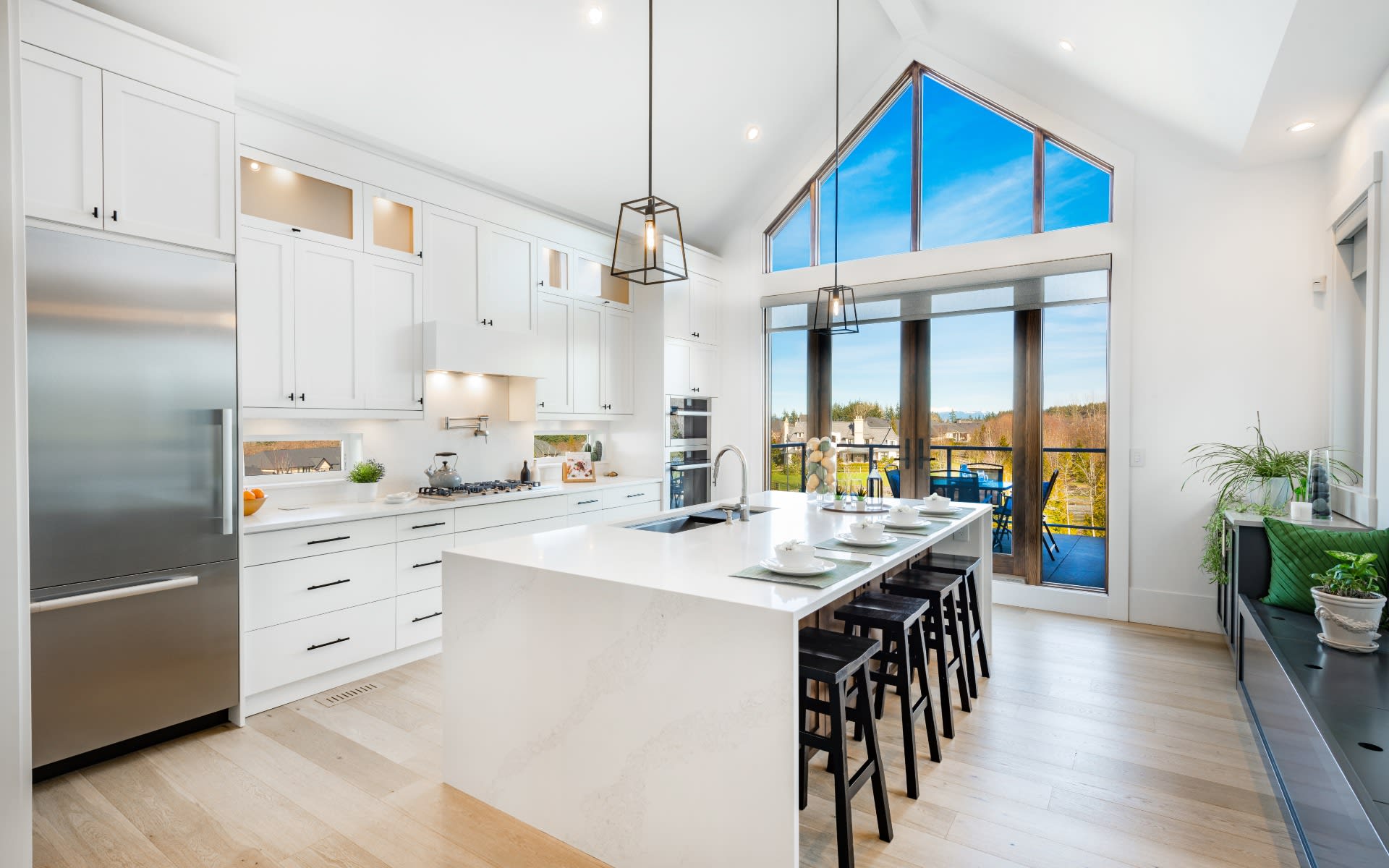 White kitchen with waterfall island, bar stools and a wall of windows to the yard