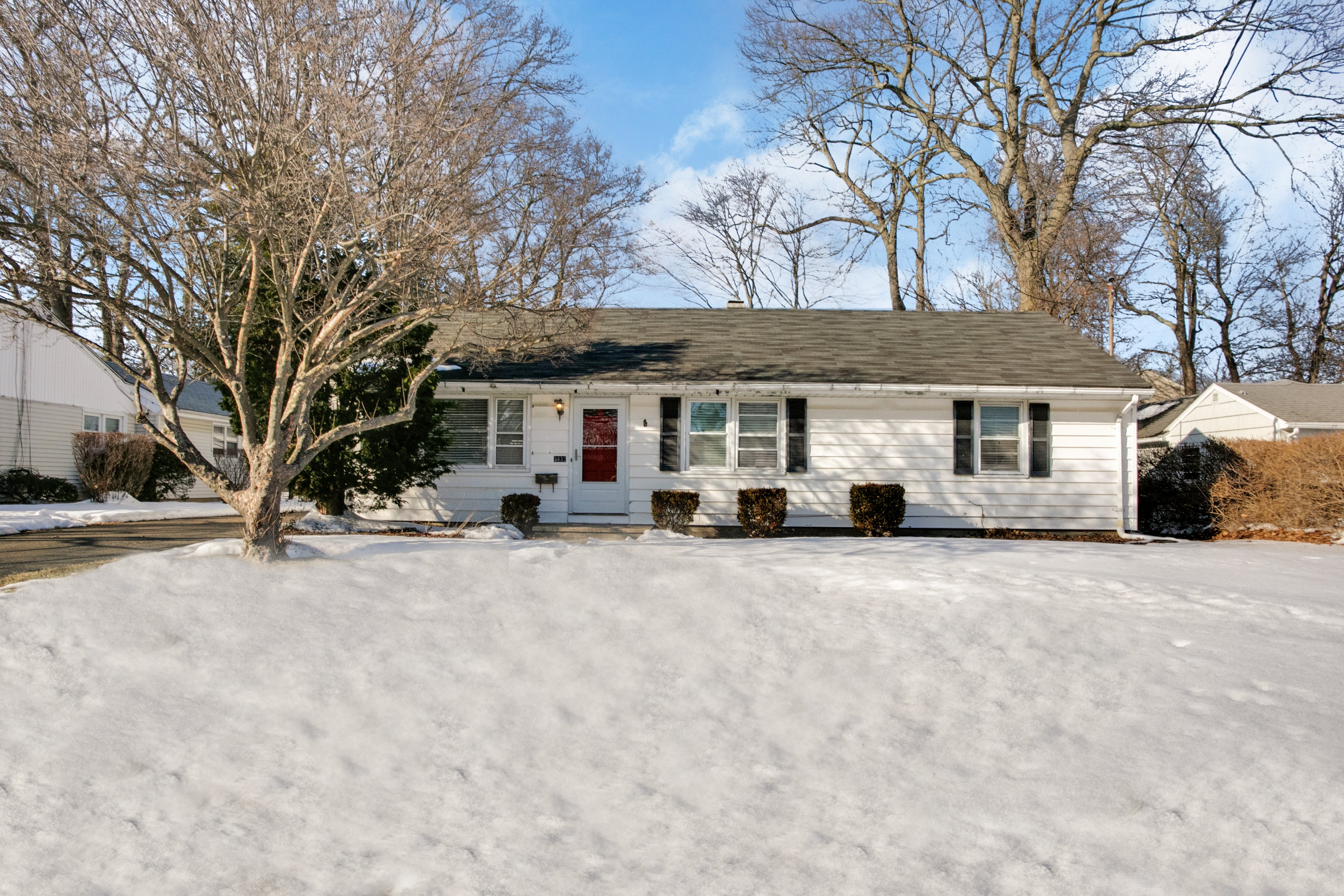 Ranch home with red front door on a snow-covered lawn at 3432 Old Town Road, Bridgeport CT
